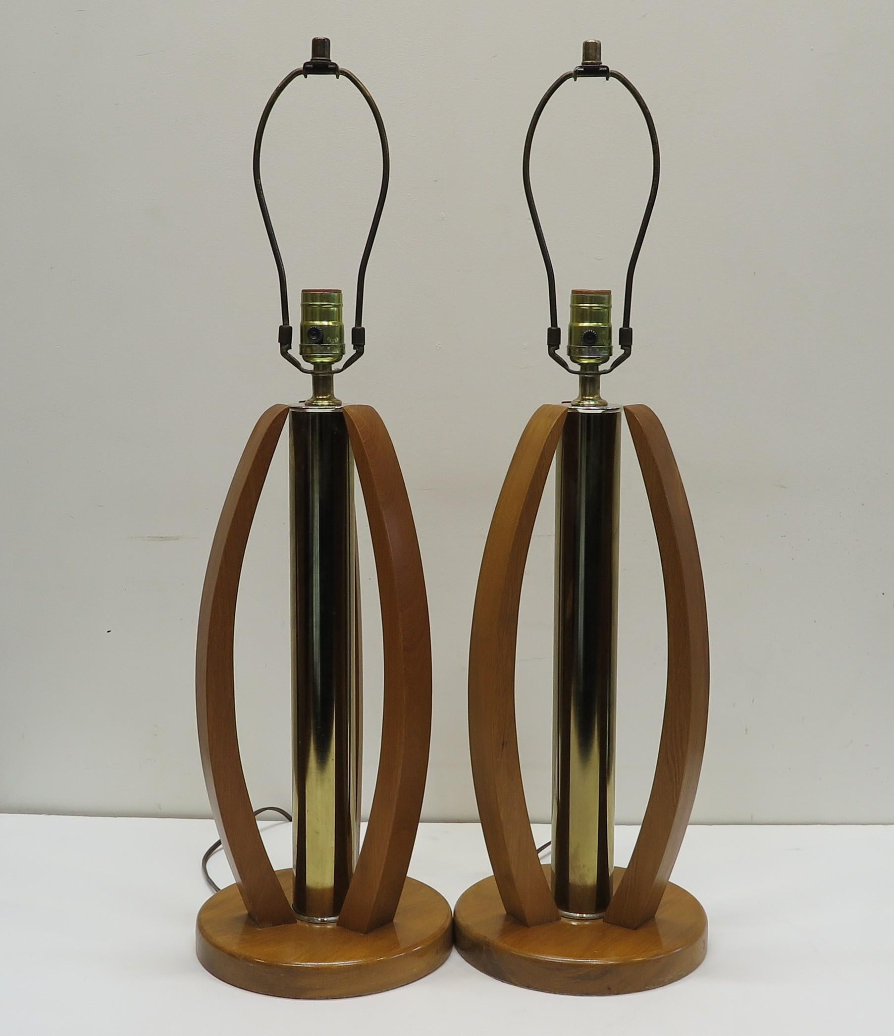 Pair of Mid-Century Modern brass & wood table lamps. Three sculpted wood surrounds with brass column in center, mid century modern table lamps. In good condition operating with a three way switch. American 1960. The listing is for a pair 2 lamps.
