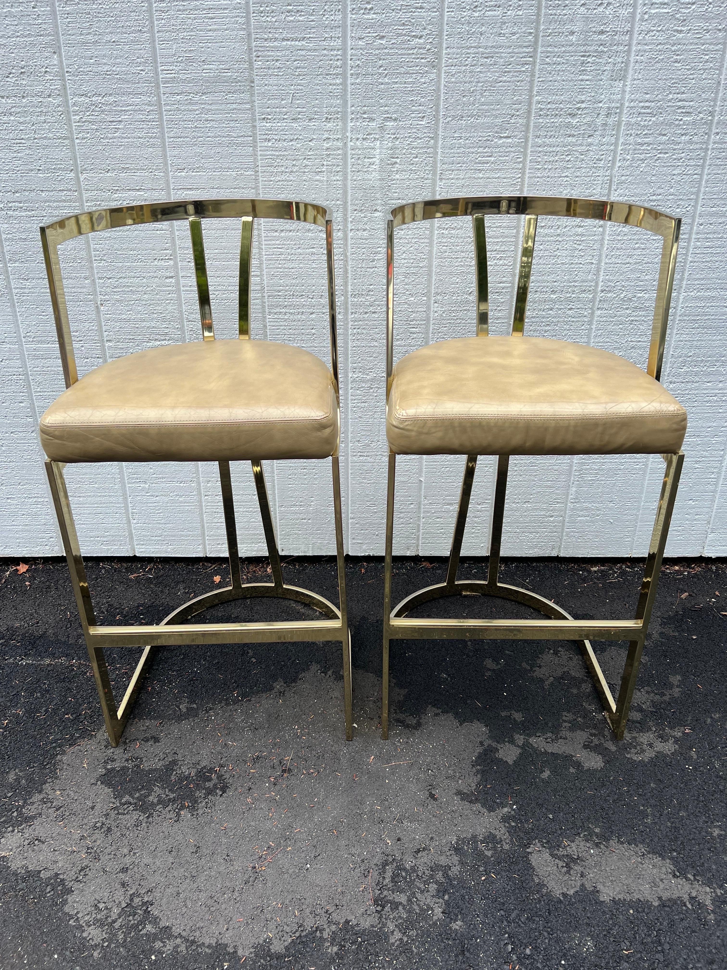 Pair of Mid-Century Modern brass bar stools by Swain. Classic, timeless style. Brass plated stools with a golden faux leather seat.