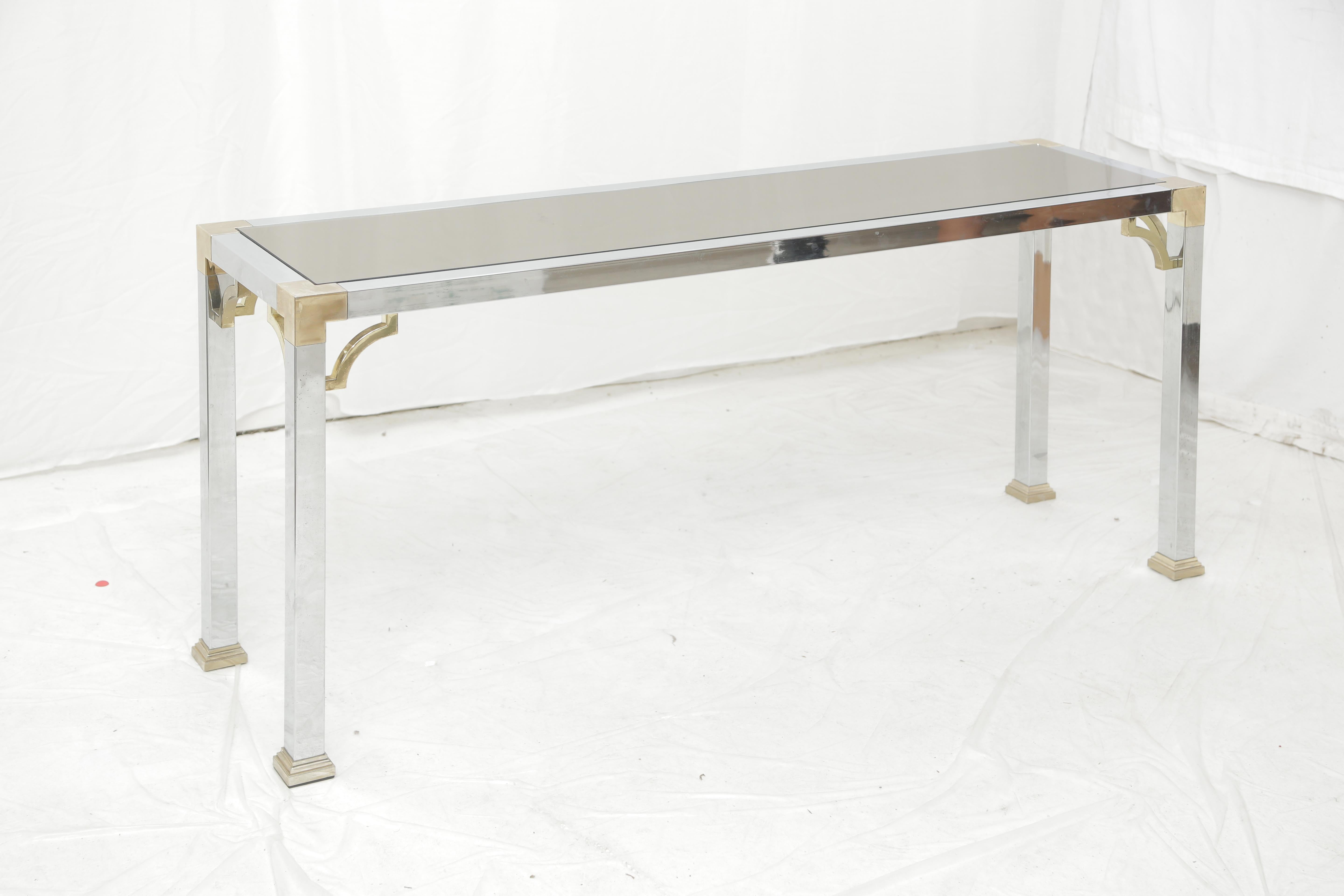 Pair of Mid-Century Modern brass and chrome console tables with a dark mirror top.
This pair of console tables will fit elegantly in an entrance or a corridor in any interior.