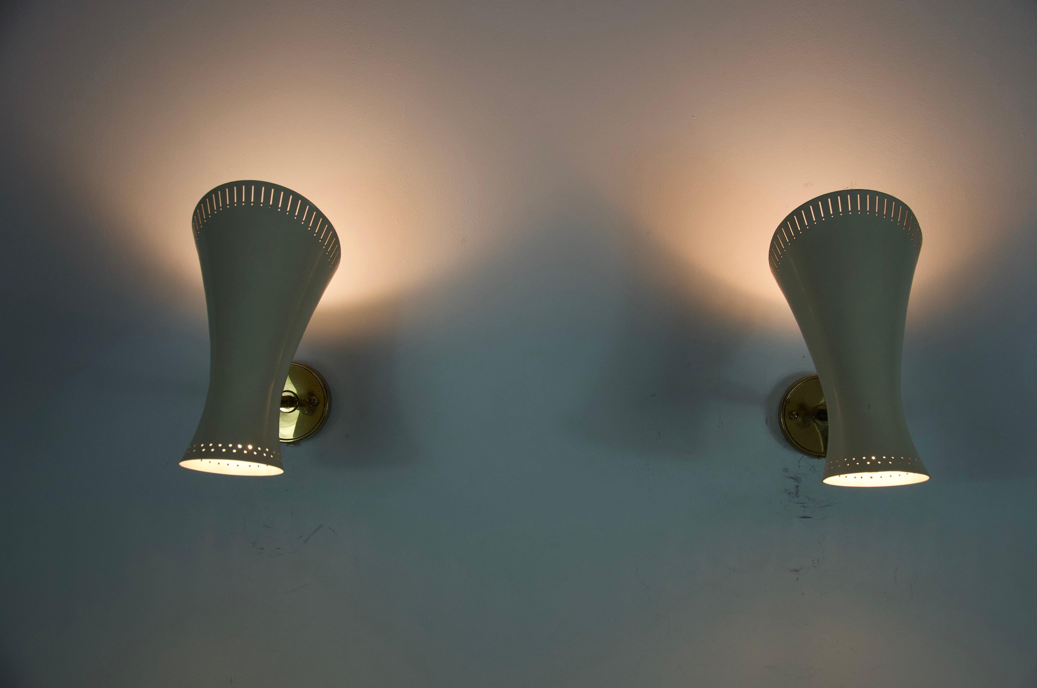 Questa coppia di lampade da parete Diabolo in ottone del Mid-Century Modern, realizzate in Germania negli anni '50, incarna l'eleganza e l'ingegno del design dell'illuminazione del dopoguerra. Ogni applique è dotata di un paralume scultoreo a forma