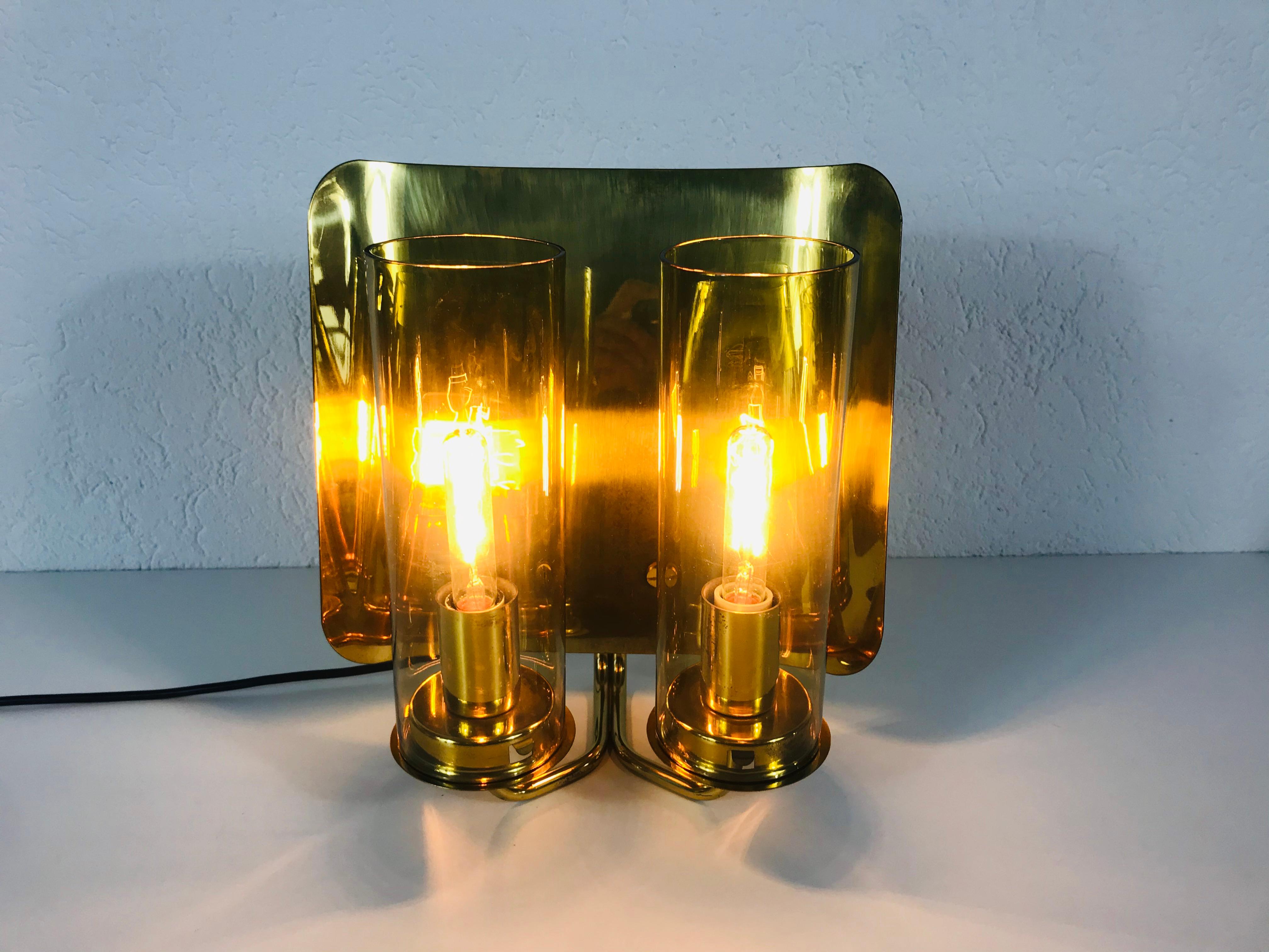 A beautiful pair of brass wall lamps made in Sweden in the 1960s. The pair has an amazing midcentury design. It is made of brass and amber glass and fits perfectly into a living room. The glass shade is very thin and elegant.

The light requires