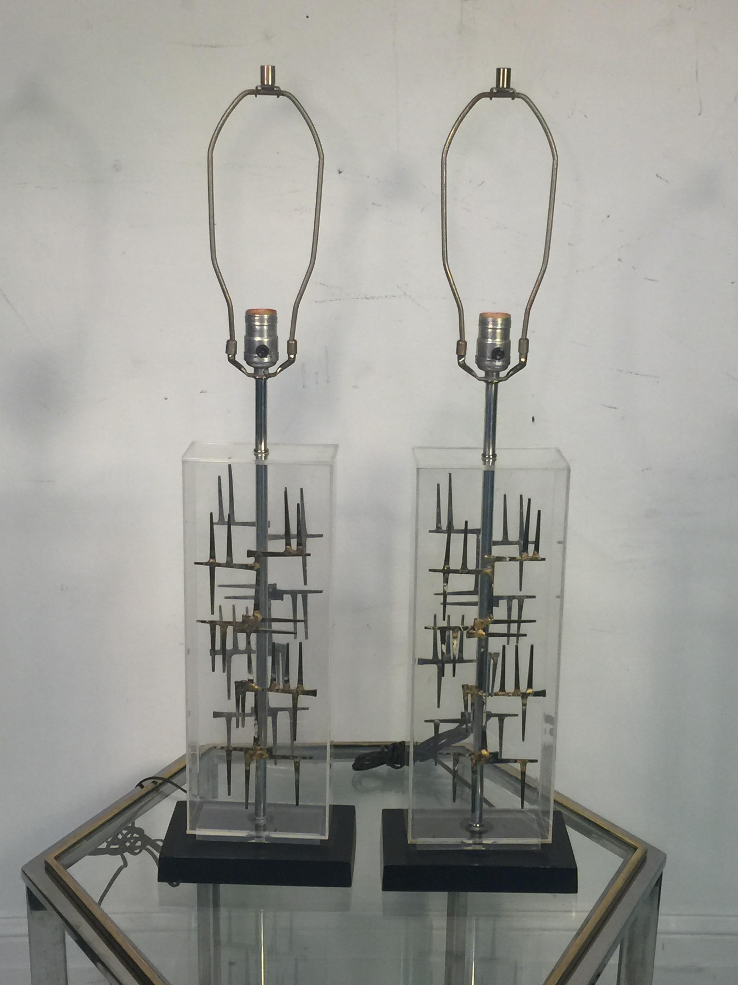 Pair of modernist Lucite rectangular form lamps with Brutalist nail design on both sides of the lamps mounted on a black enameled metal rectangular base designed in the 1960s.The Lucite lamp body measures at 18