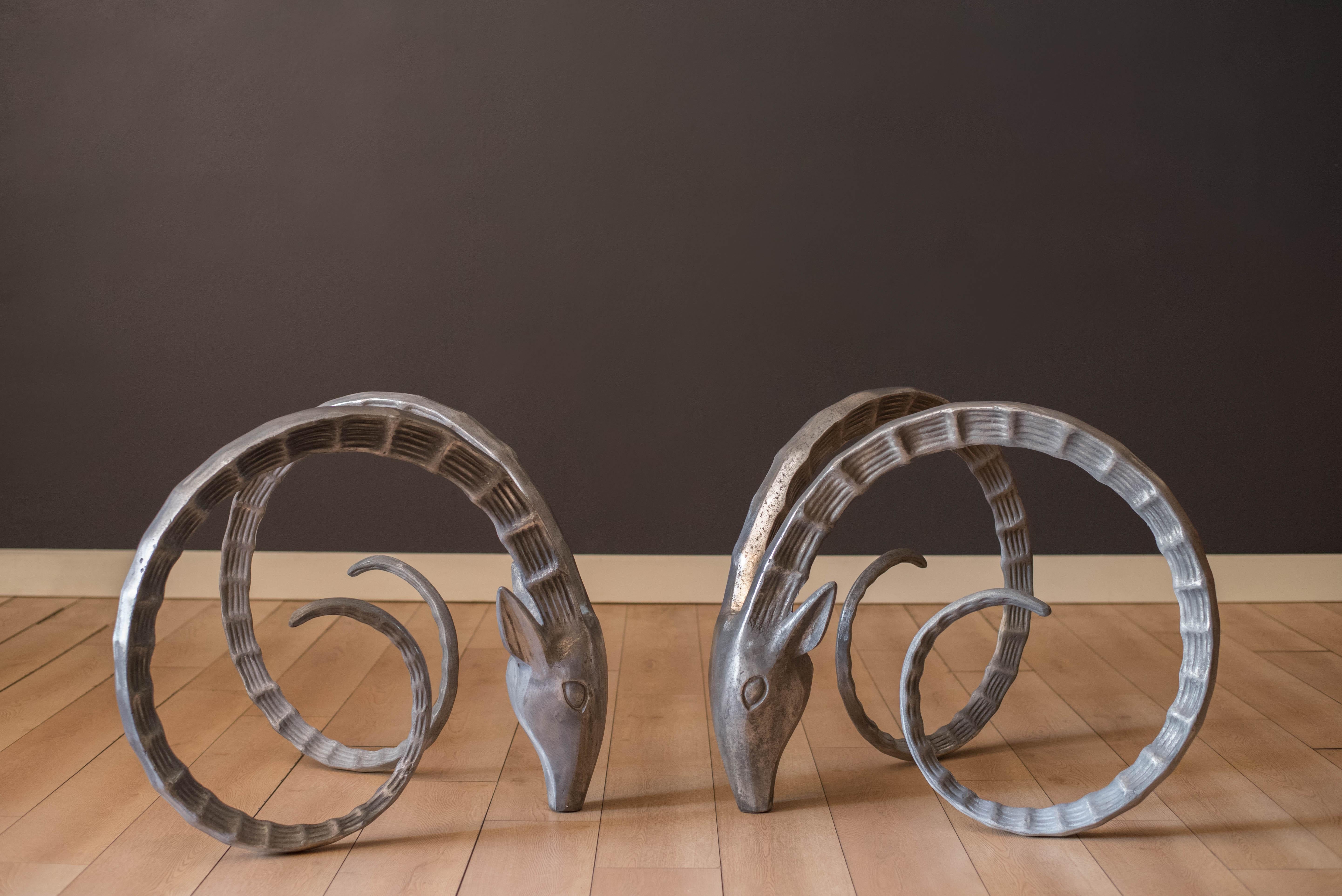 Vintage Ibex Rams head cast aluminum sculptures in the manner of Alain Chervet, circa 1970s. This sophisticated and dramatic focal point will be a statement piece in any interior dining room space. Price is for the bases only, glass top is not