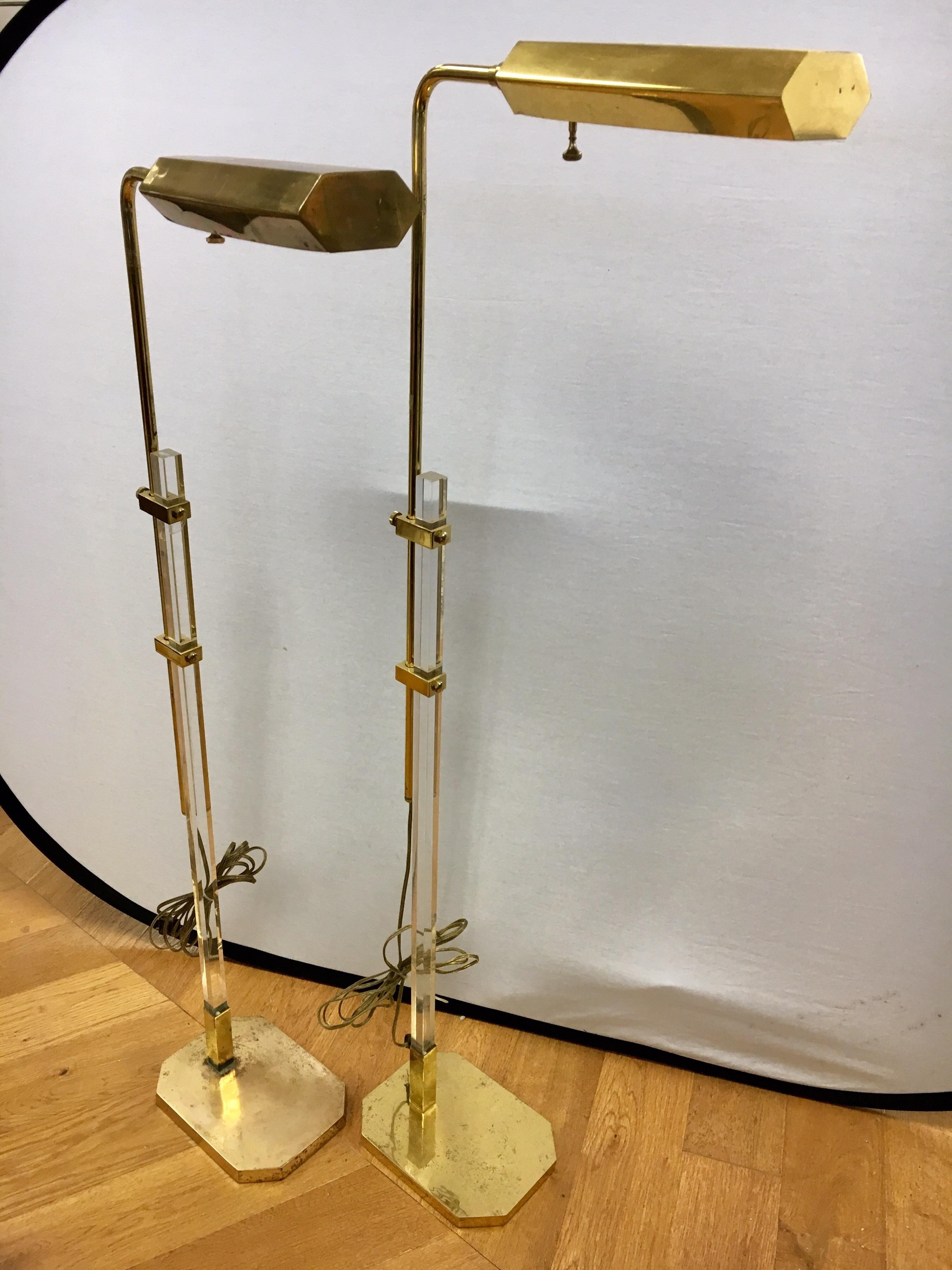Pair of matching brass and Lucite floor lamps. They swivel and adjust at height.
They are true period pieces from the 1970s and do have tarnish on brass base,
one more than the other.