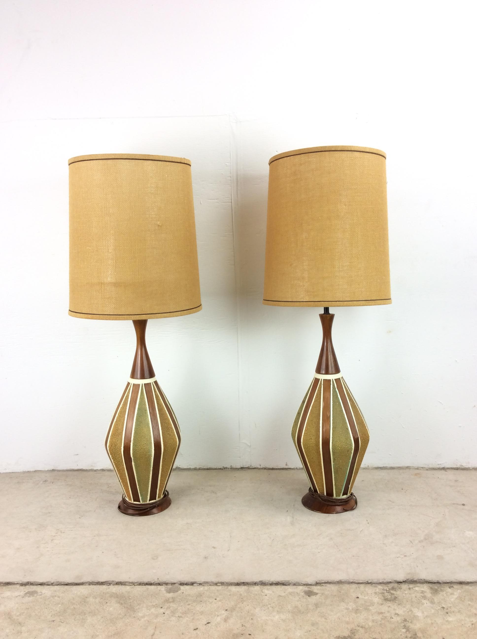 This pair of mid century modern table lamps feature painted ceramic body with wood veneer detailing with a turned wood neck and base.

Dimensions: 9w 9d 41h
Shade diameter: 13.5 inch

Condition: The vintage wiring on this pair of lamps works. The