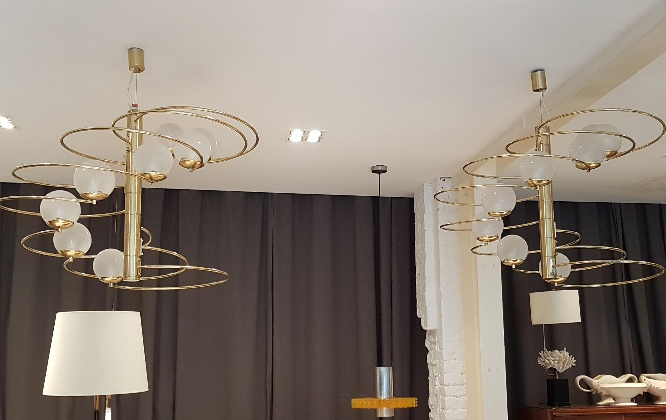A pair of elegant Italian sculptural chandeliers designed by Pia Guidetti Crippa for Lumi, Milan, circa 1960s Italy, label to stem. These chandeliers have a brass stem with eight opaque glass shades on each chandelier. Makers label to stem.