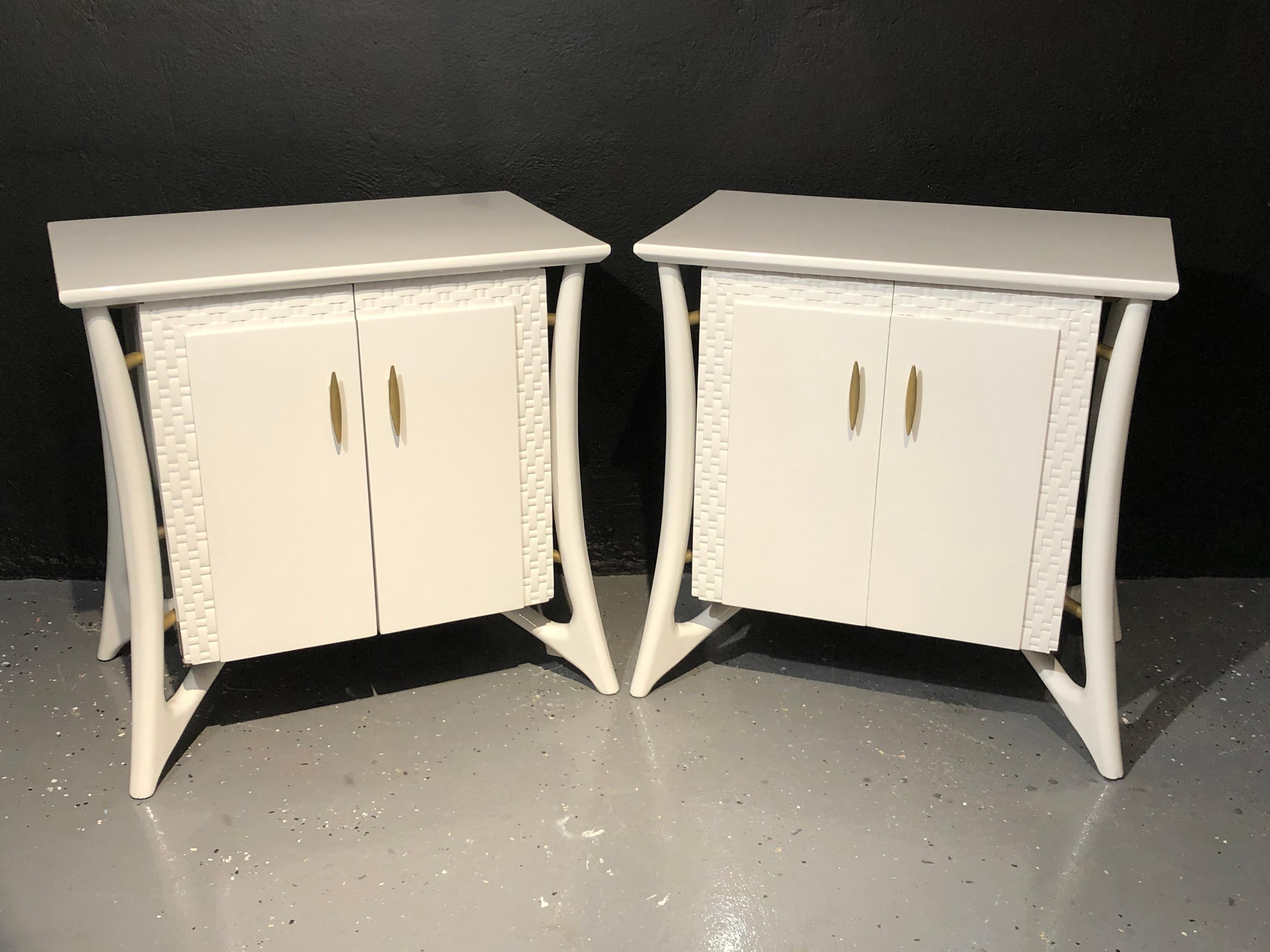 Piet Hein attributed Mid-Century Modern chests, nightstands or end tables. A recently pale gray lacquered pair of nightstands or end tables. Each case having two doors with flanking carved mesh framing and gilt metal pulls leading to an open