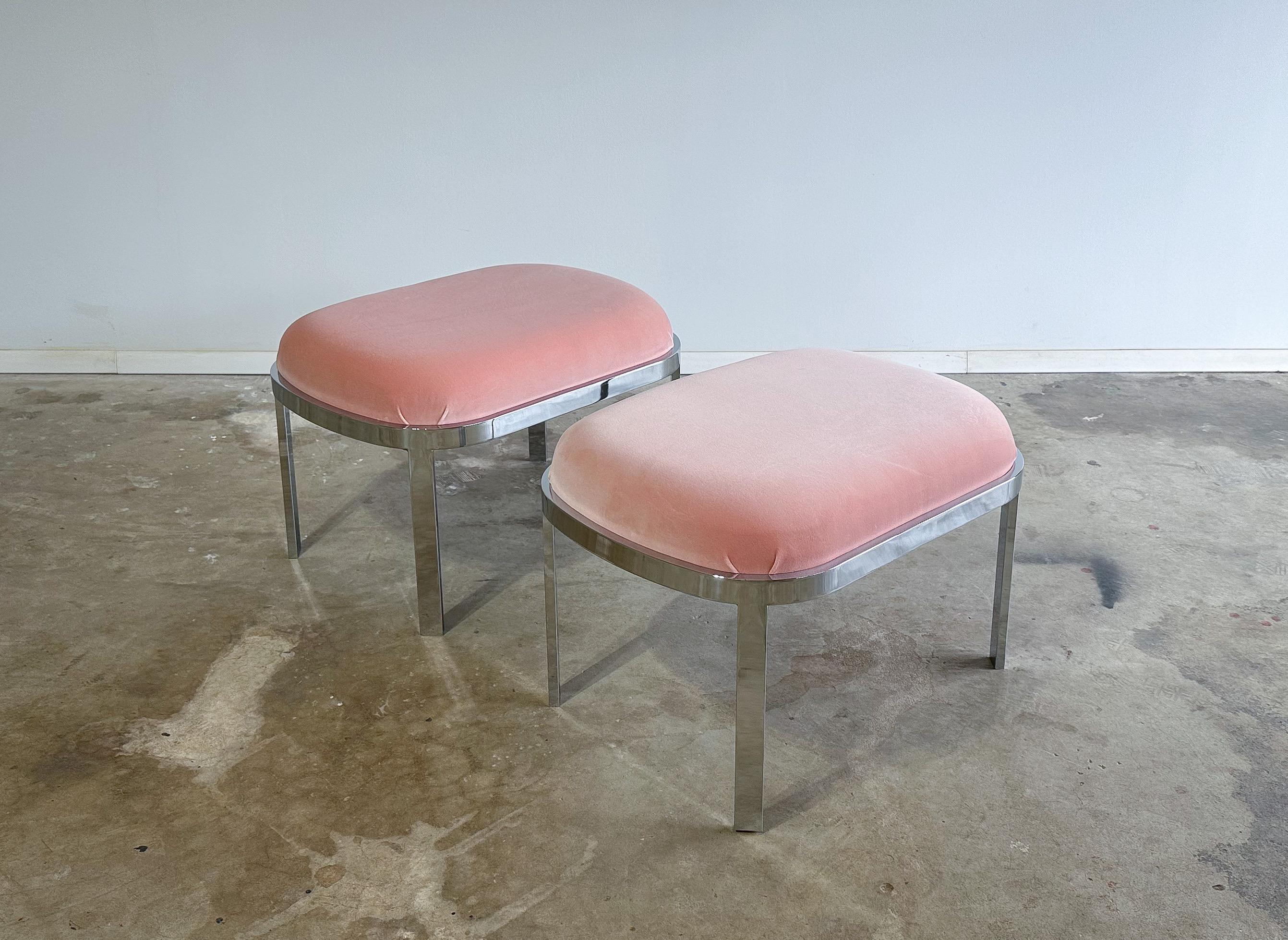Offered is a pair of vintage chrome stools or ottomans in the style of Milo Baughman. Featuring well constructed, heavy gauge chromed steel frames, and freshly upholstered seats in a beautiful blush pink velvet. These would be perfect as functional