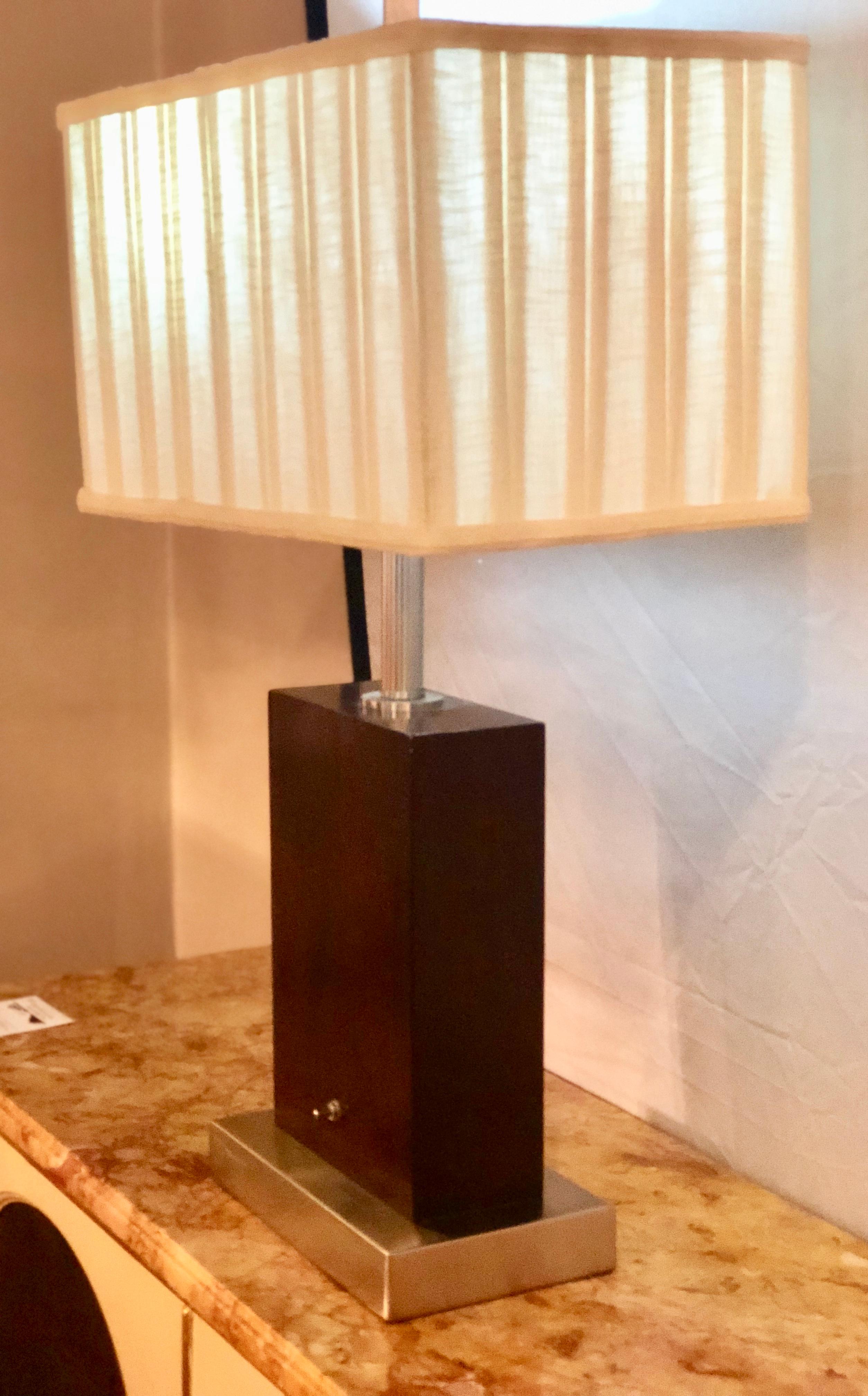 A pair of Mid-Century Modern chrome and wood base table lamps with matching custom shades. The chrome base leading to a mahogany square column pedestal with a chrome pole supporting the custom lampshade. Takes, at least, two 60 watt bulbs.