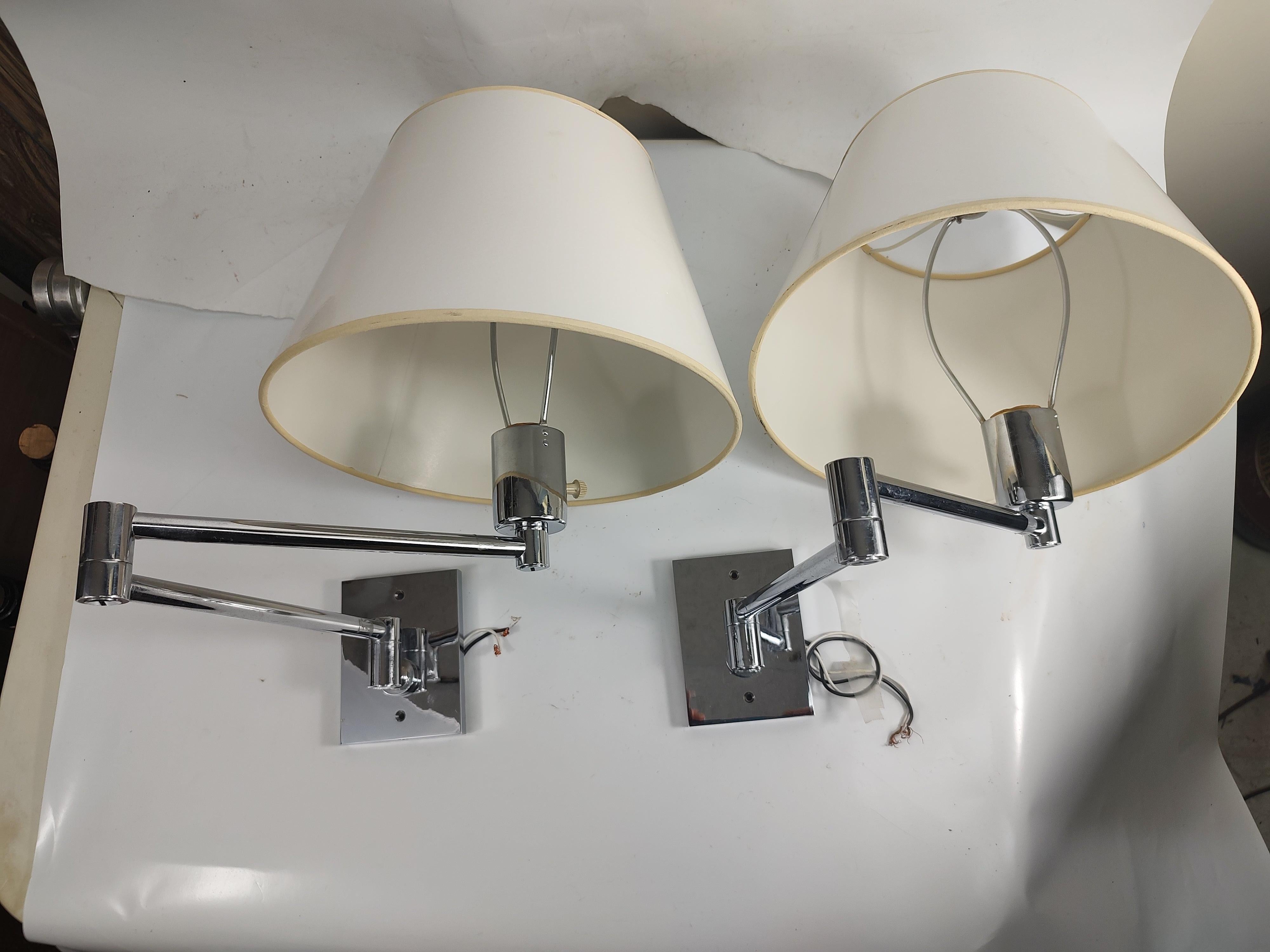 Fantastic pair of high quality chrome swing arm wall sconces by the Hansen Lighting Co, made in Spain c1965. Includes original lacquered paper shades and not original pair of acorn finials. Priced and sold as a pair. In excellent vintage condition