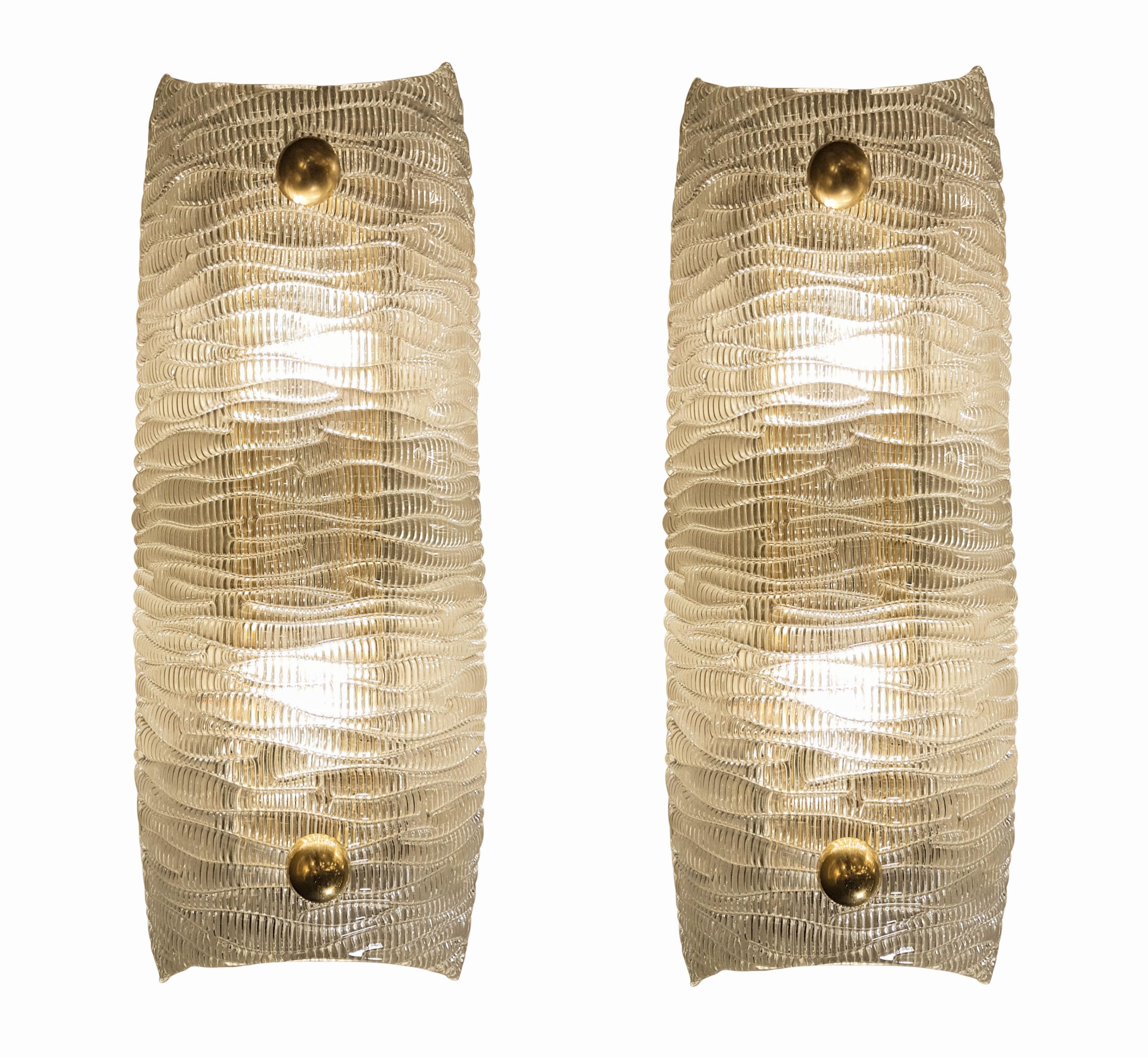 Pair of Mid-Century Modern clear textured Murano glass sconces, brass mounts.
The Murano glass is clear with a pattern in relief, which makes it translucent when lighted.
2 candelabra base lights each, rewired.
They are attributed to Barovier e