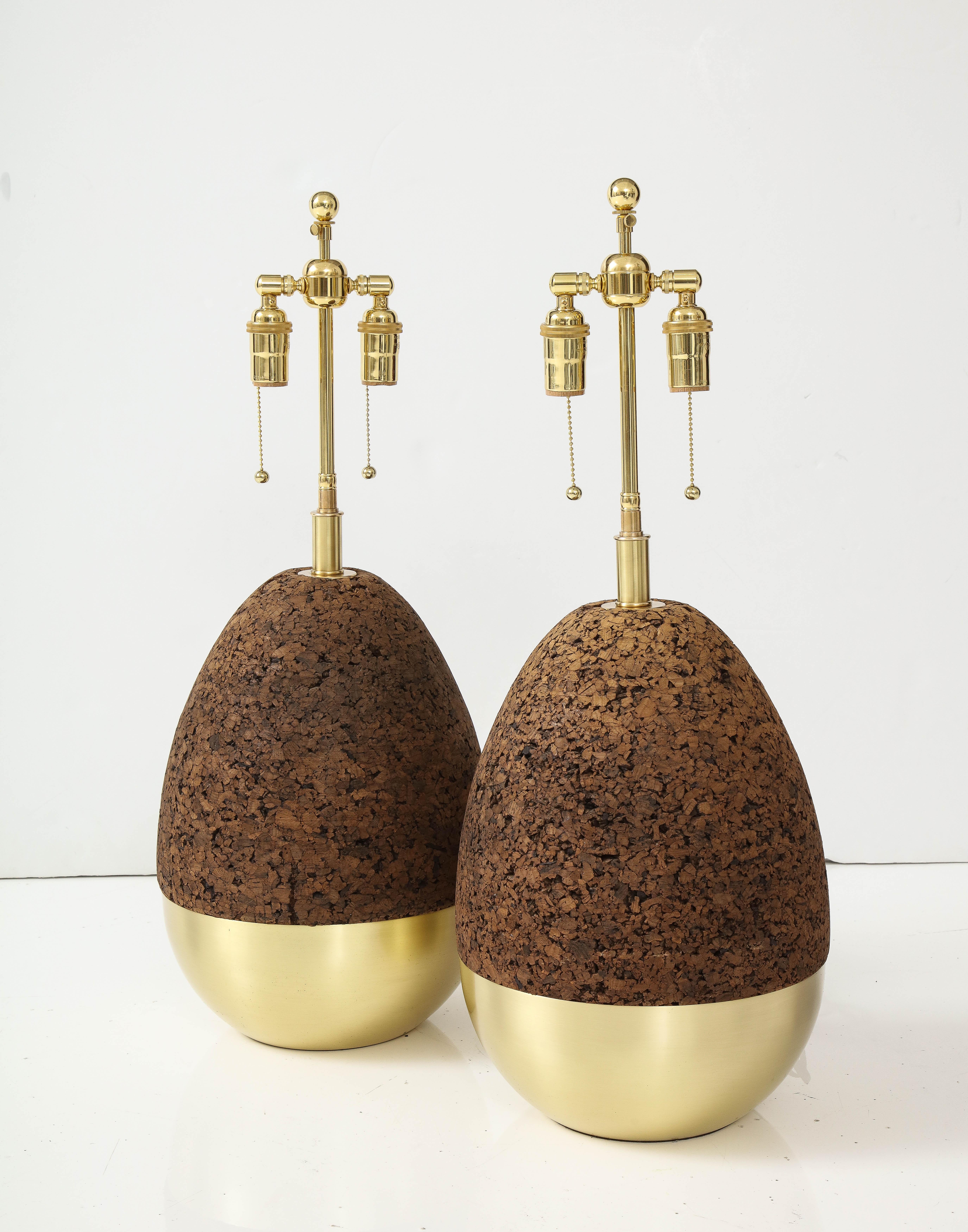 Pair of midcentury 1970s Egg shaped brass and cork table lamps.
The lamps have been Newly rewired with adjustable polished brass double clusters that take standard Size light bulbs and silk rayon cords.
The height to the top of the finial is 28.5