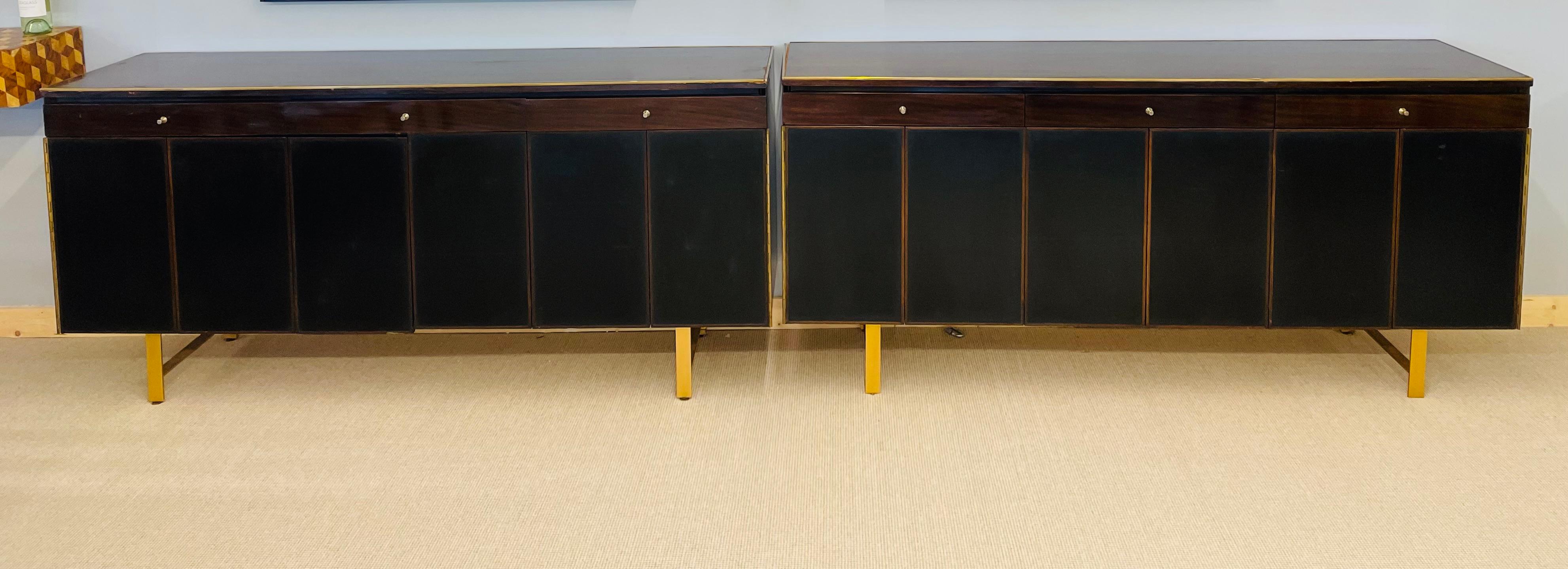 Pair of Mid-Century Modern credenzas / sideboards by Paul McCobb. Large and impressive pair of sideboards or credenzas by this highly sought after designer. The pair having Piano Hinged doors and brass framed tops with interior shelves under a set