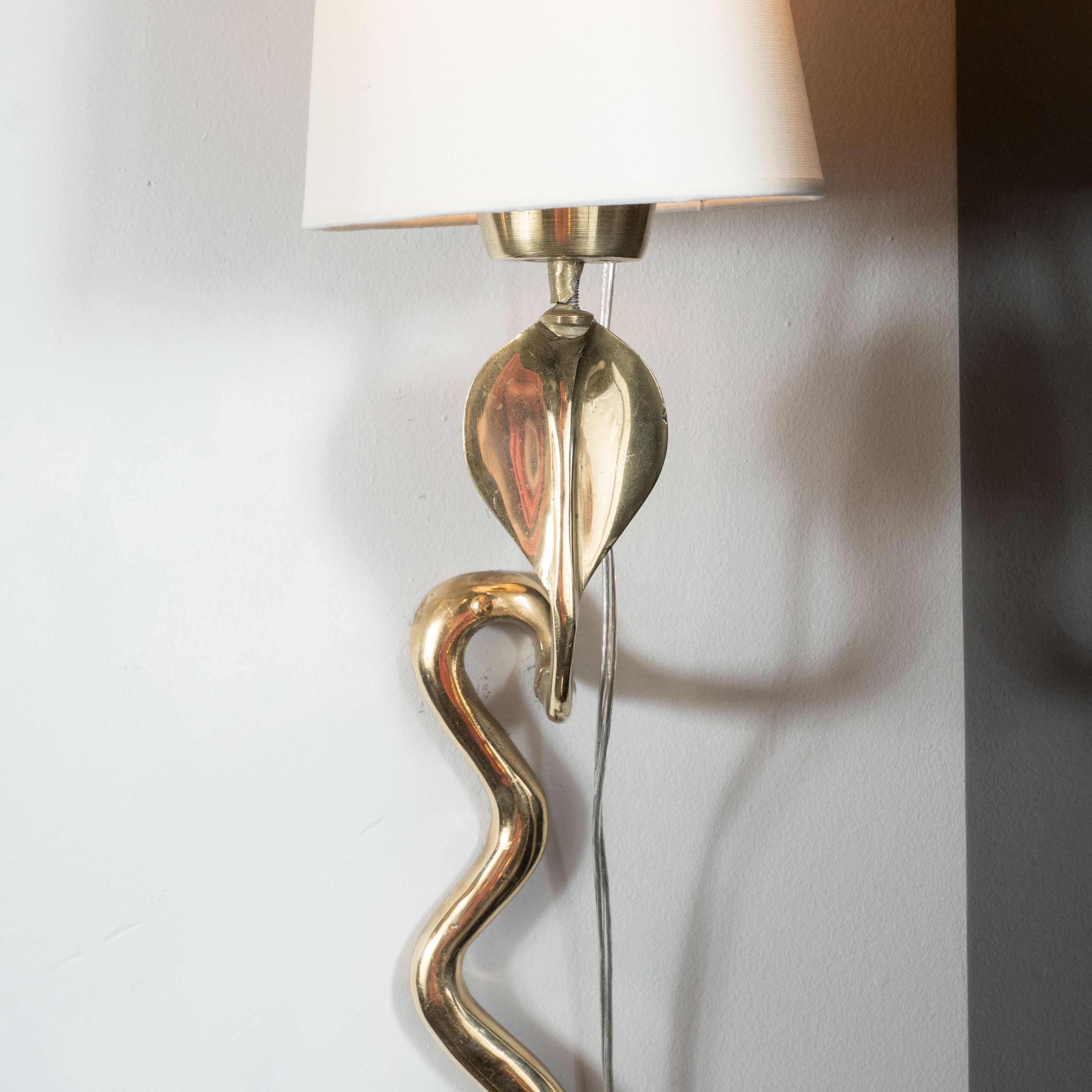 This stunning pair of Mid-Century Modern brass sconces were realized in the United States, circa 1960. They feature stylized interpretations of cobra snakes offering sinuously curved cylindrical forms that taper to its tale representing the