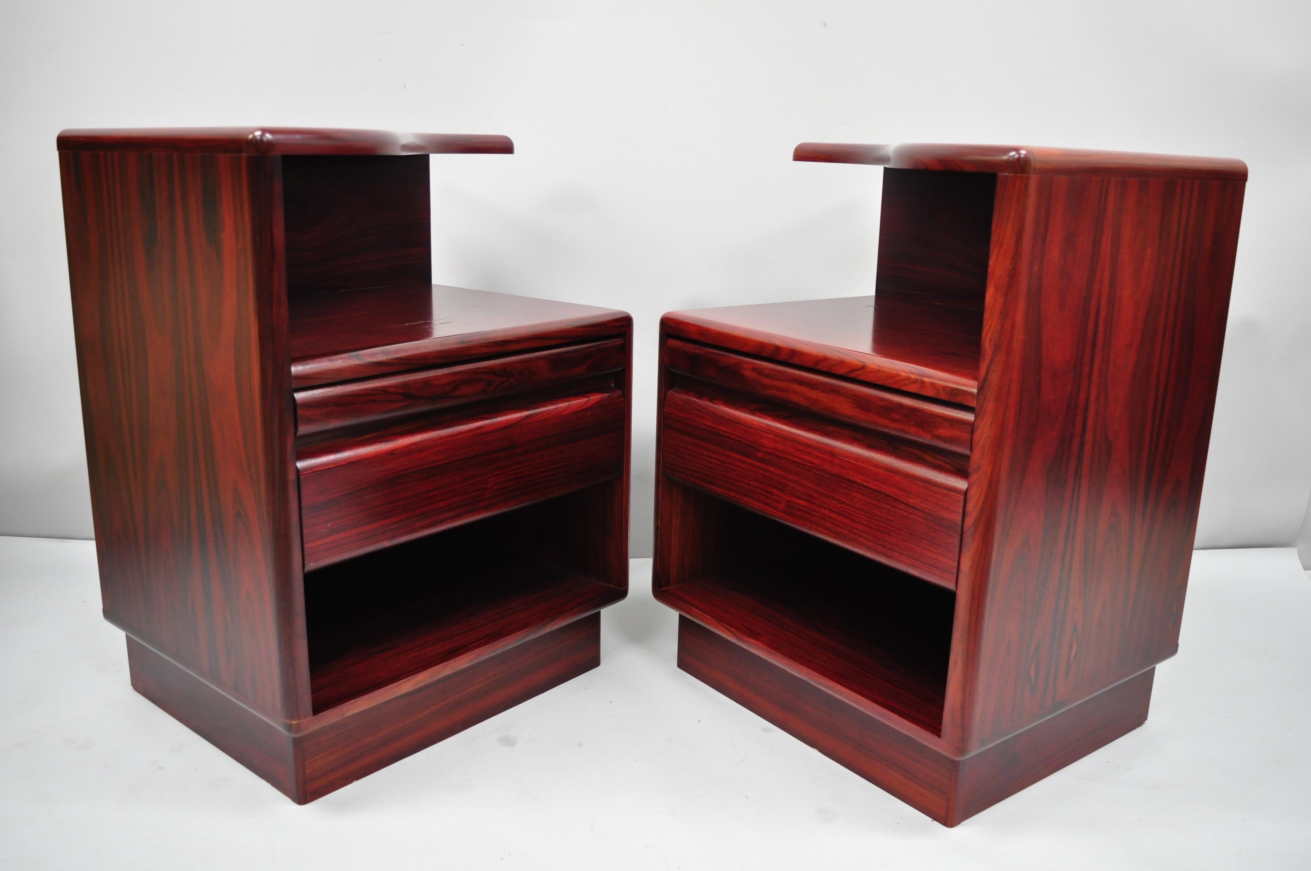 Pair of Mid-Century Modern Danish modern rosewood nightstands tables by Mobican. Items feature pullout surface, shaped tops, one drawer, beautiful wood grain, original label, clean modernist lines, sleek sculptural form, circa late 20th century.