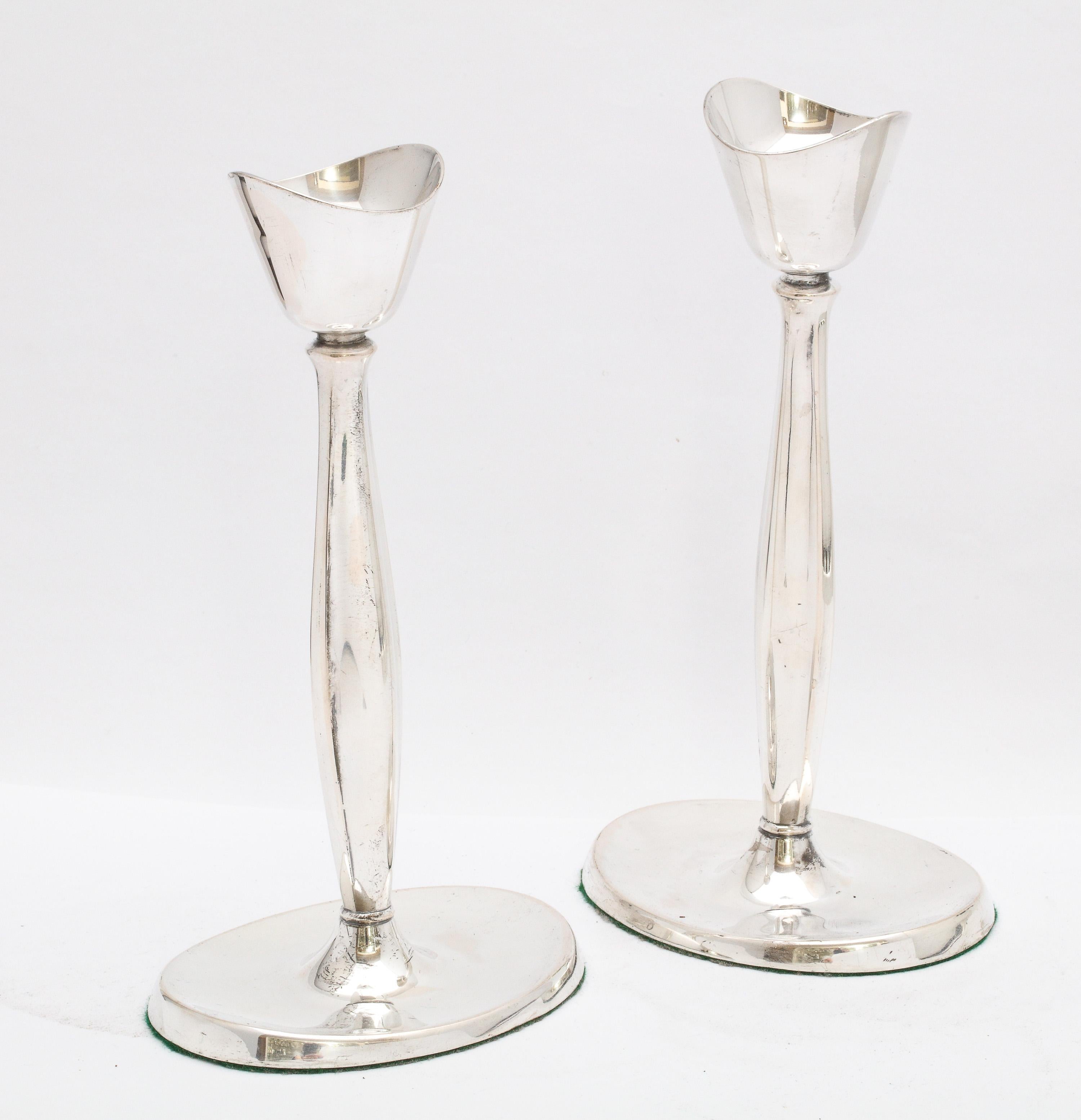 Pair of Mid-Century Modern, sterling silver candlesticks, Denmark, Ca. 1940's, Cohr - maker. Graceful design, each candlestick having an oval base and lightly fluted column. Each candlestick measures 7 1/2 inches high x 4 inches wide (across oval