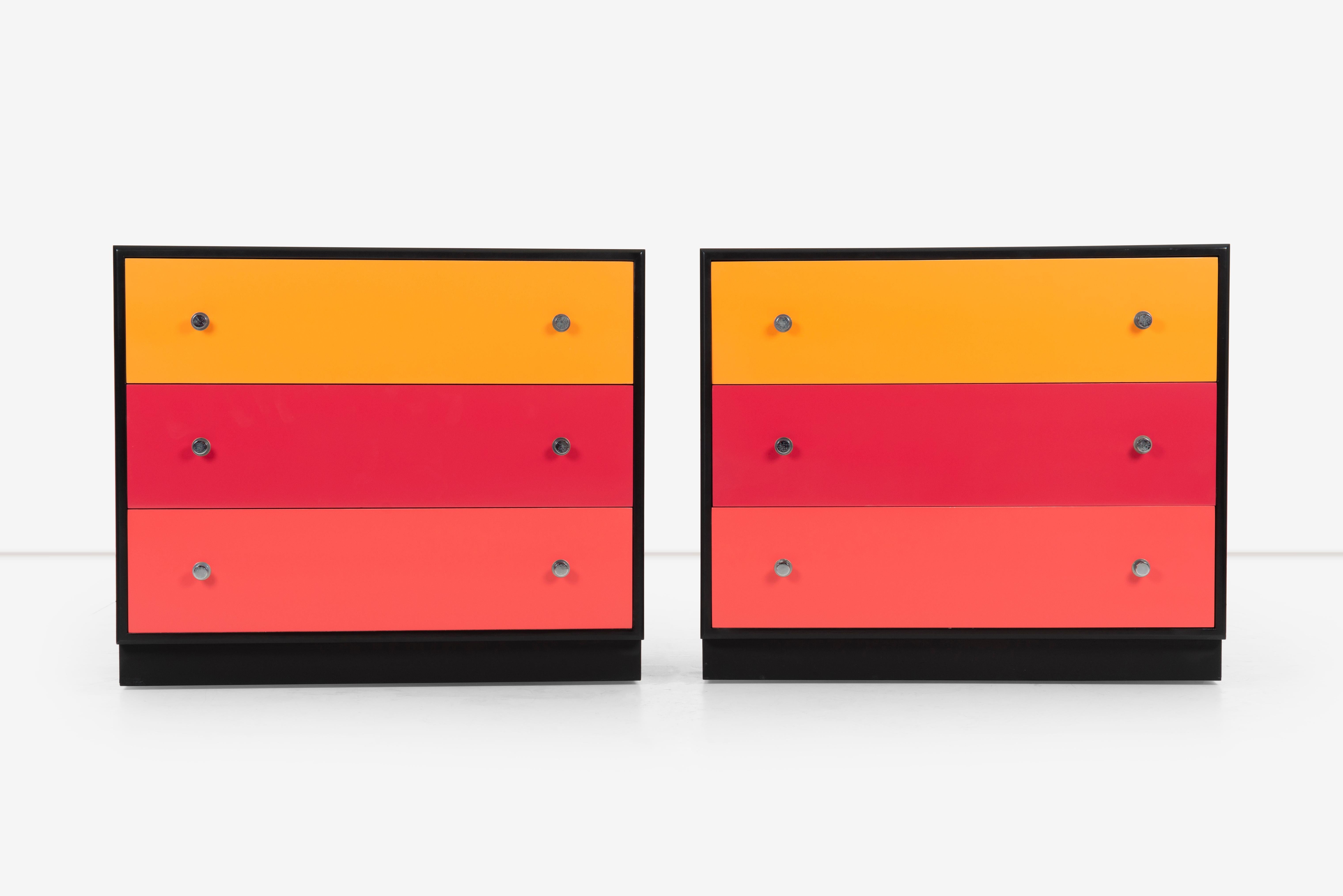 Pair of mid-century modern dressers refinished with Alexander Girard colors of inspiration. Features a black body with an orange, strawberry, and grapefruit colored drawer, with chrome plated pulls. Minor ware through out the case piece expected