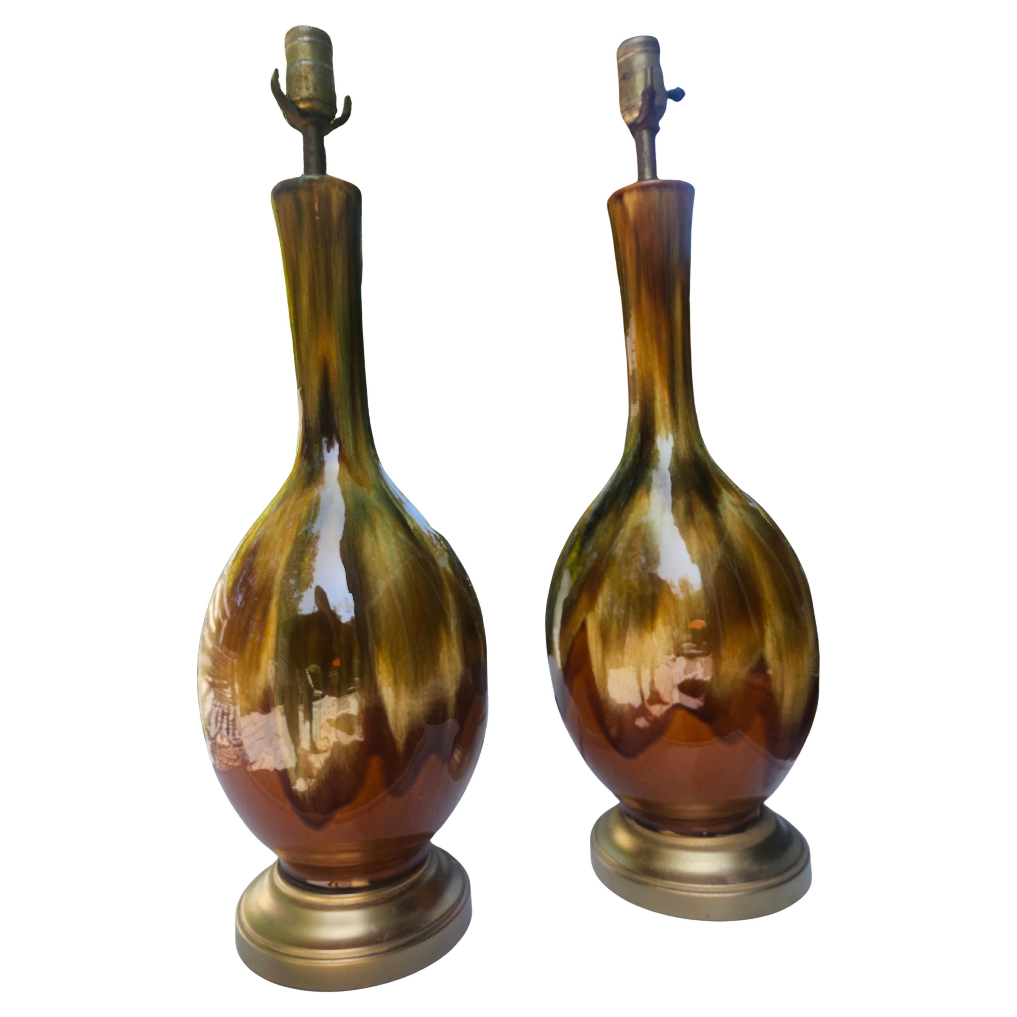 Very nice pair of Mid-Century Modern pottery lamps with a drip glaze in a rainbow of greens yellows and browns. Beautiful coloring sitting on freshly painted gold  metal plinths. Original wiring is sound, harps will be supplied but no shades. In