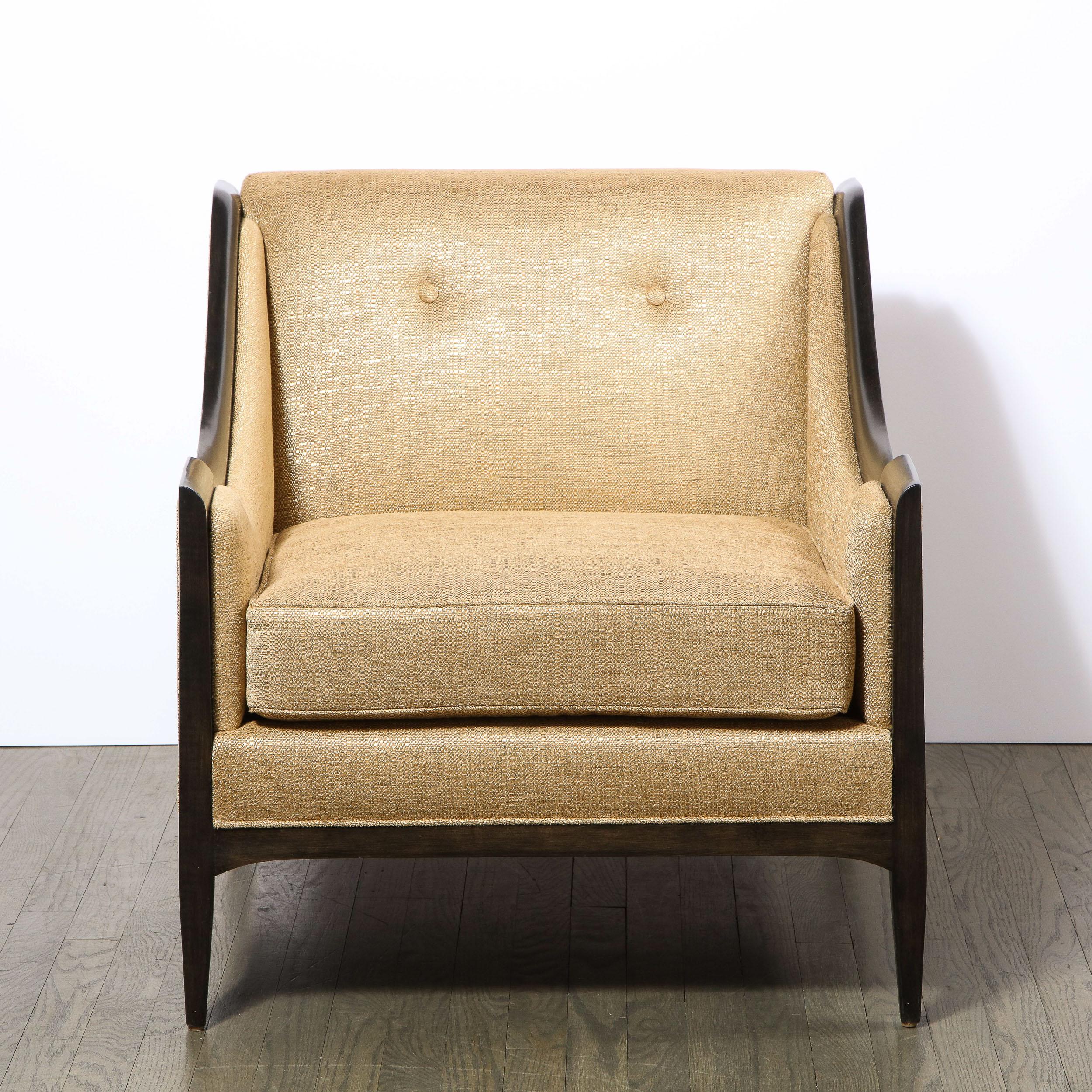 This elegant pair of Mid-Century Modern club chairs were realized in the United States circa 1960. They offer arched hind legs; tapered cylindrical front legs; a square back; scalloped sides framed in hand rubbed ebonized walnut. Additionally, they