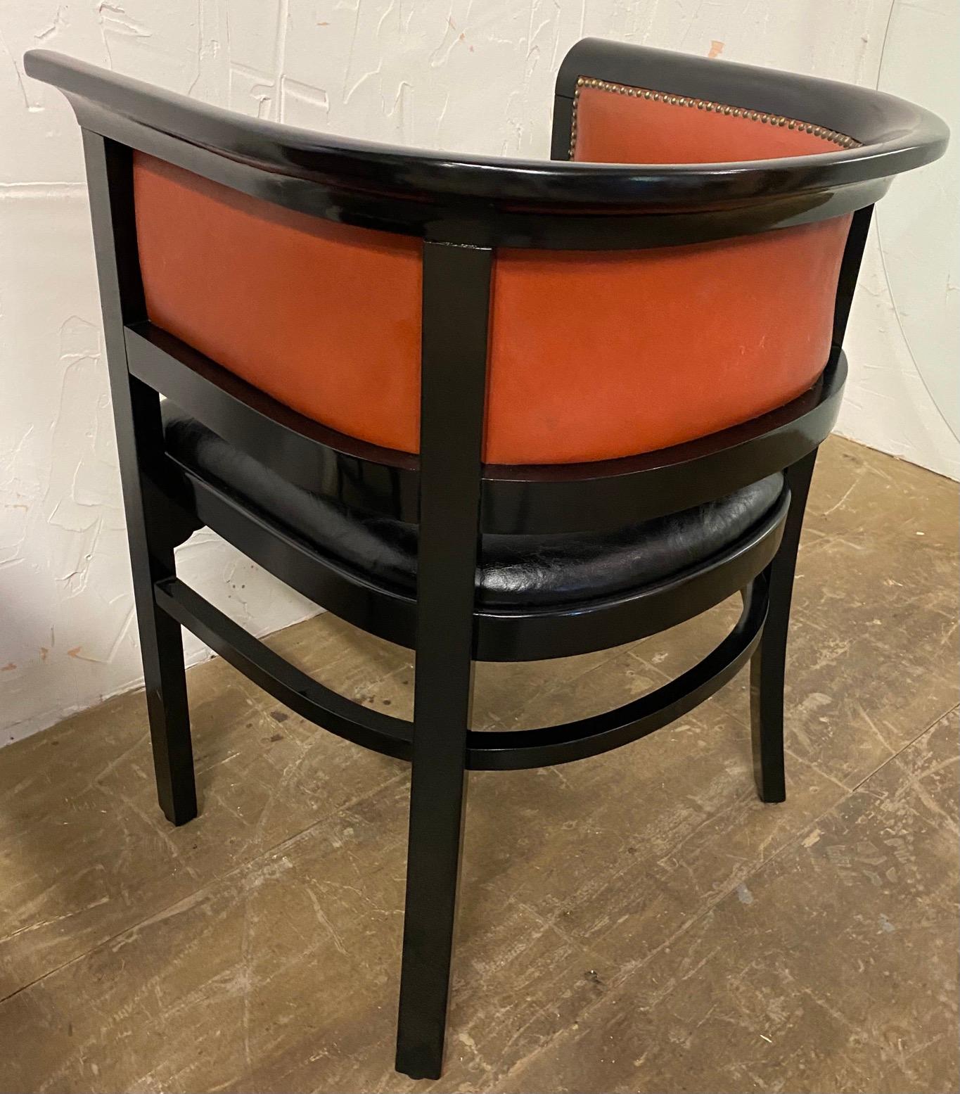 Pair of stylish vintage Mid-Century Modern C formed black wood frame orange toned leather back and black seat. 
Search terms: Art Deco style arm chairs, Horseshoe chairs, club chairs, lounge chairs, arm chairs, Martini Modern Style Chairs, barrel