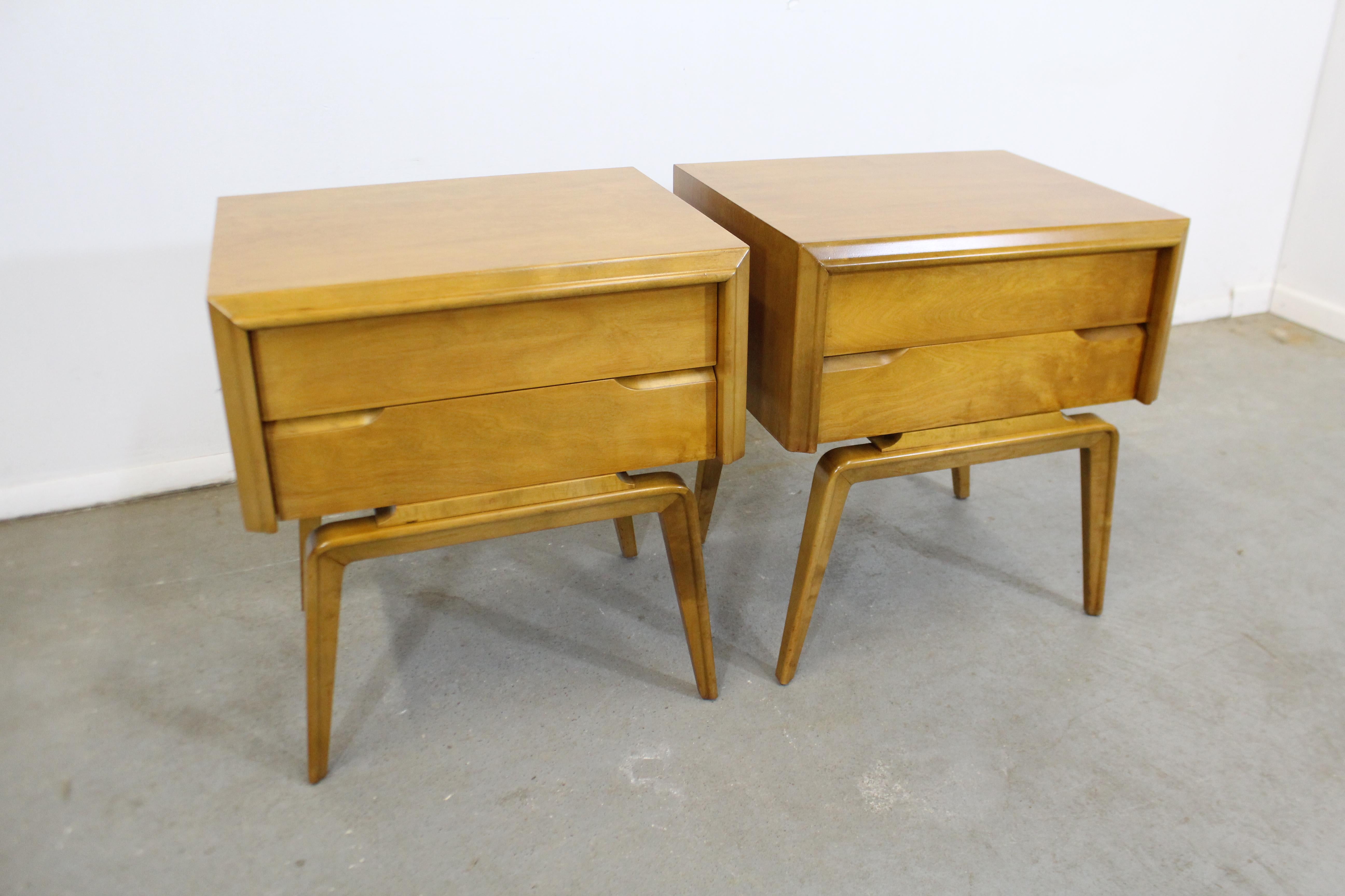 Offered is a pair of midcentury nightstands with sleek lines designed by American designer Edmond J. Spence. Made from yellow birch, these stands feature beautifully sculpted legs and two dovetailed drawers with hidden pulls. They have been