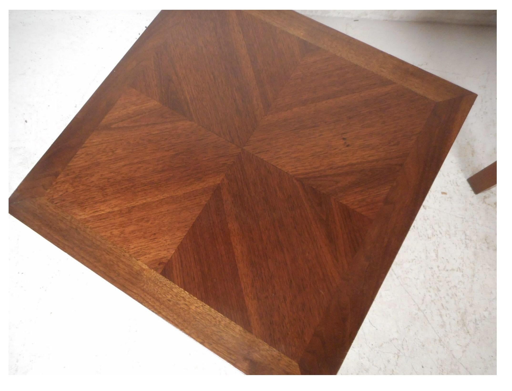 Precioso par de mesas auxiliares vintage modernas con vetas únicas de madera de nogal en distintas direcciones en la parte superior. Un maravilloso diseño de forma cuadrada ayuda a que esta pieza quepa en lugares cómodos y ofrece mucho espacio para