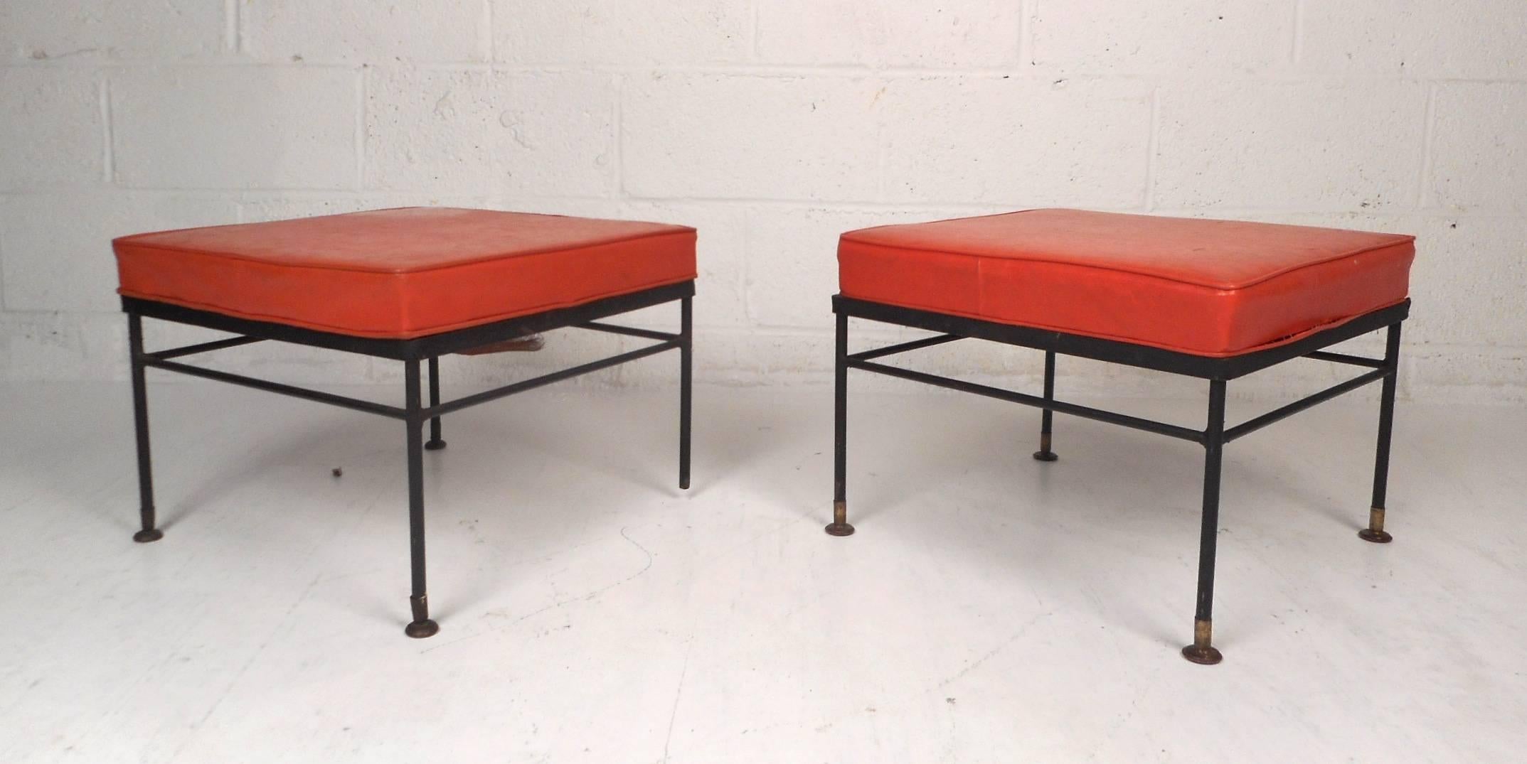 This lovely pair of vintage ottomans feature a unique iron base with a thick padded cushion on top covered in elaborate orange vinyl. This wonderful pair of midcentury stools make the perfect addition to any modern interior. Please confirm item
