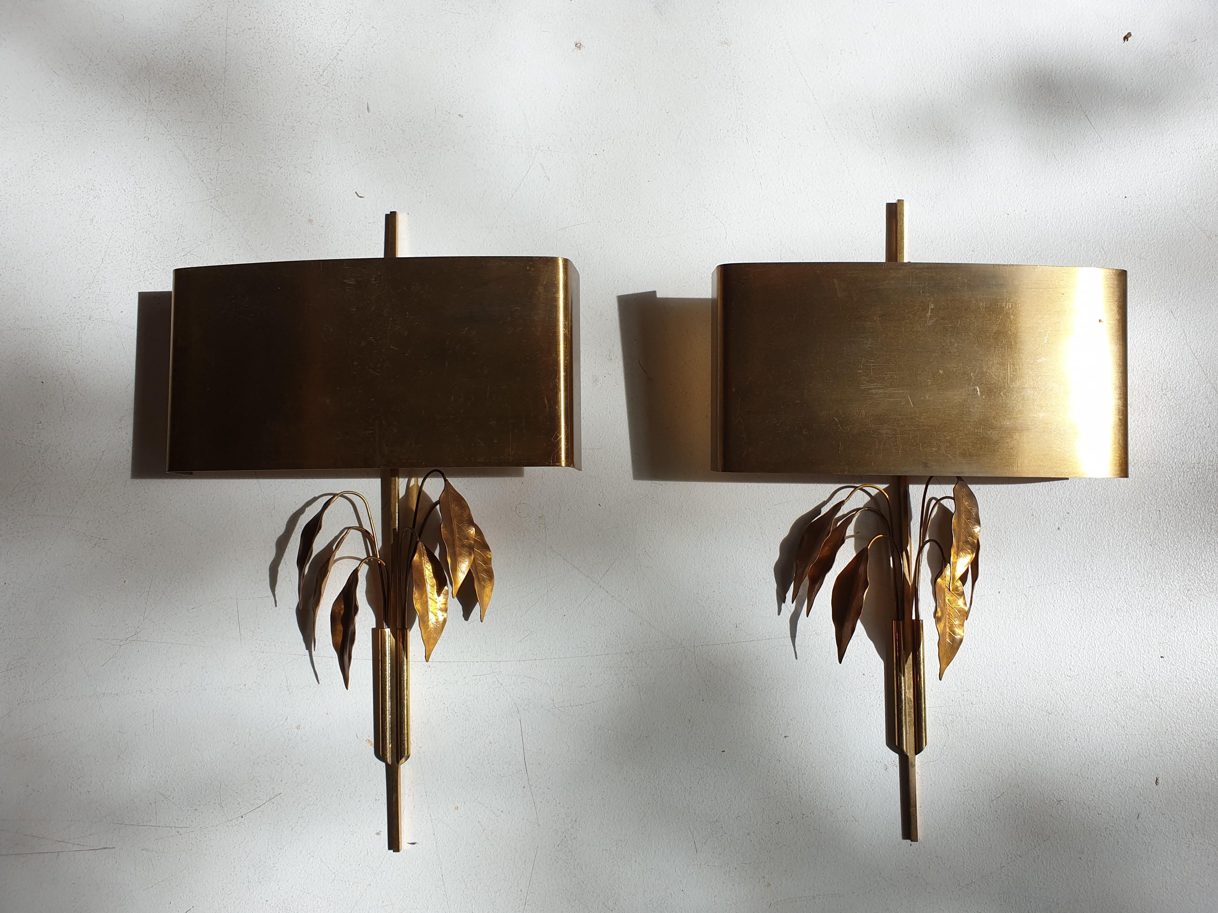 Pair of French lacquered brass wall lights with brass shades and stems adorned with delicate sprays of leaves.