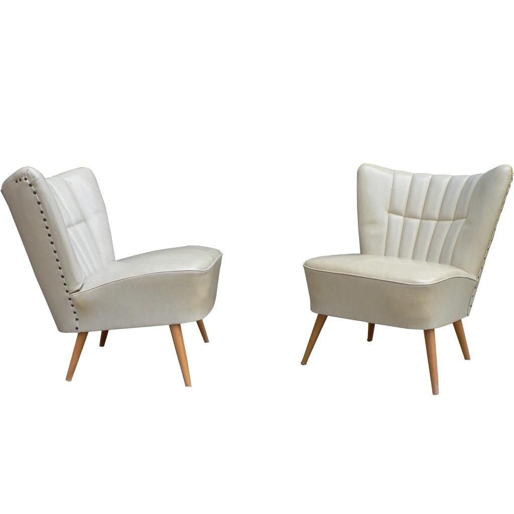 Pair of Mid-Century Modern cocktail chairs. This pair of vintage chairs feature an off white shell back cocktail with original leatherette (skai) upholstery. Made in France circa 1050. Extremely comfortable.
   