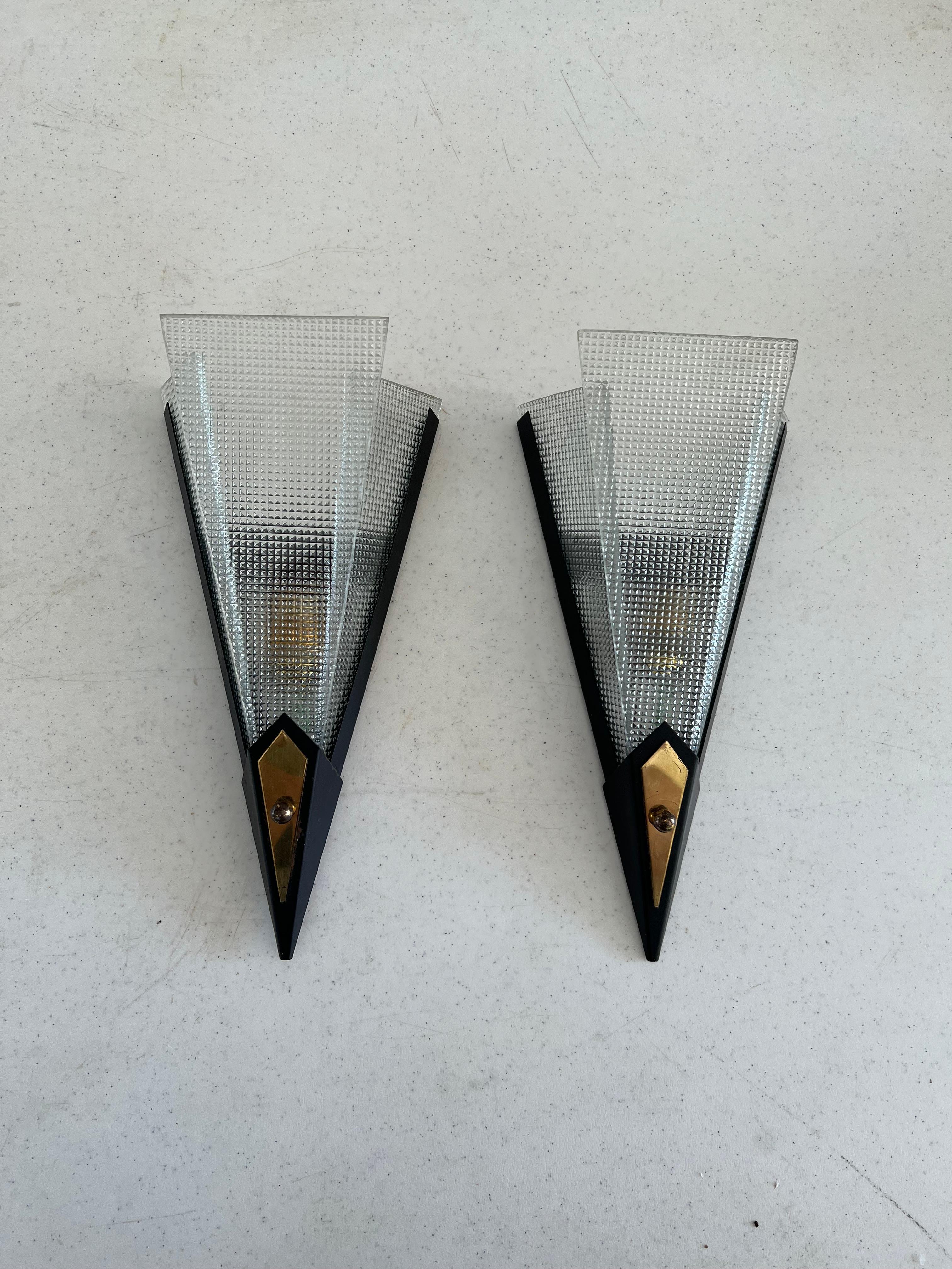 Pair of Modernist Sconces in brass, black lacquered metal body and frosted pressed glass.
 manufactured in France, circa 1950.
There are 6 pressed glass panels.
They each hold one bayonete bulb but this can be updated to an E14 socket if desired