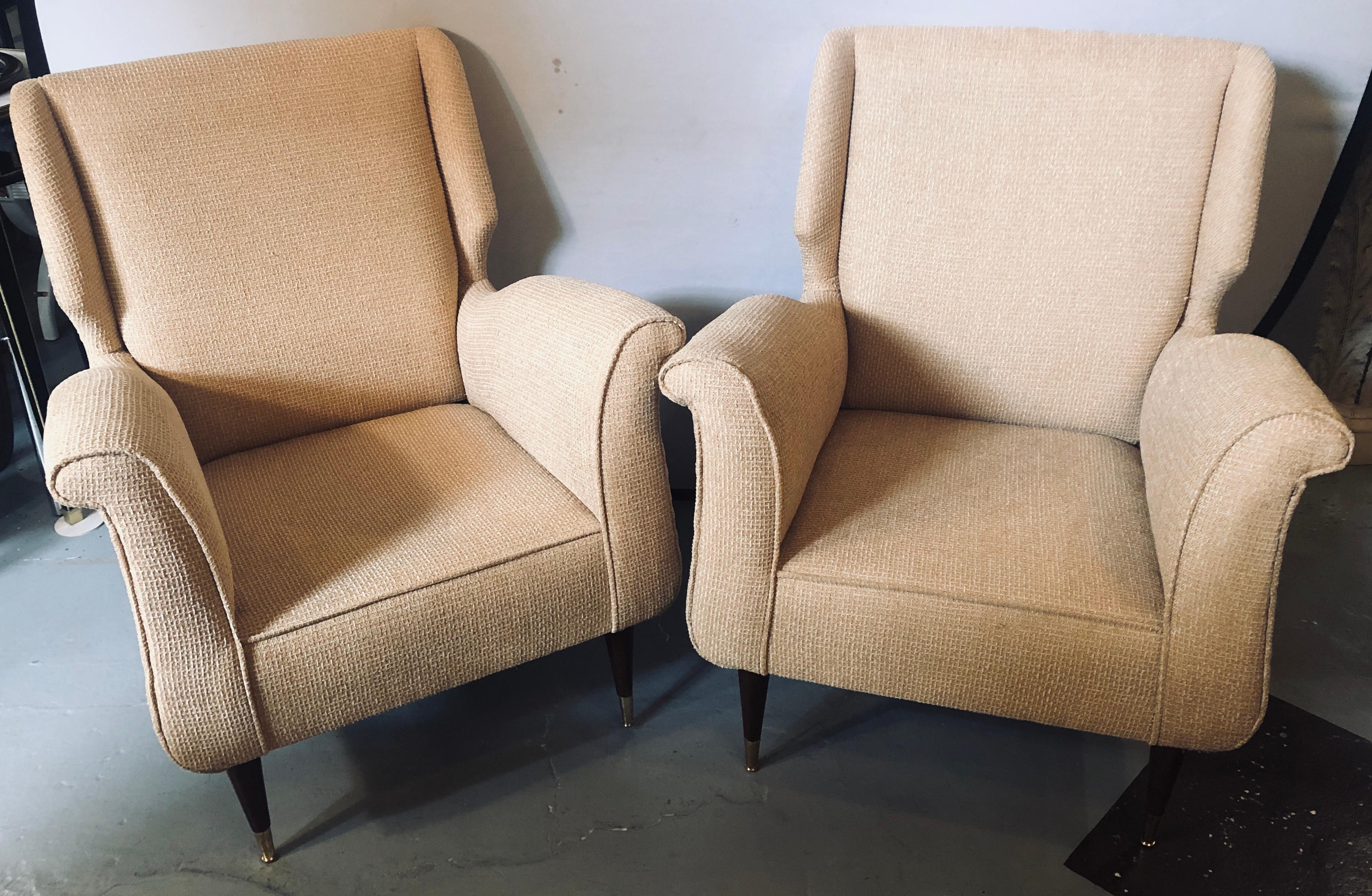 Pair of Mid-Century Modern Gio Ponti style arm or wing back chairs. These finely detailed sleek and stylish arm chairs depict this iconic designers style for flair and simplicity at his highest level. The tapering mahogany legs sitting on brass