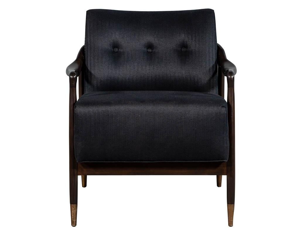 Pair of sleek Mid-Century Modern club chairs, with a beautifully sculpted walnut show wood frame accented with brass caps and head to head hand applied upholstery tacks upholstered in a rich pinstripe fabric.