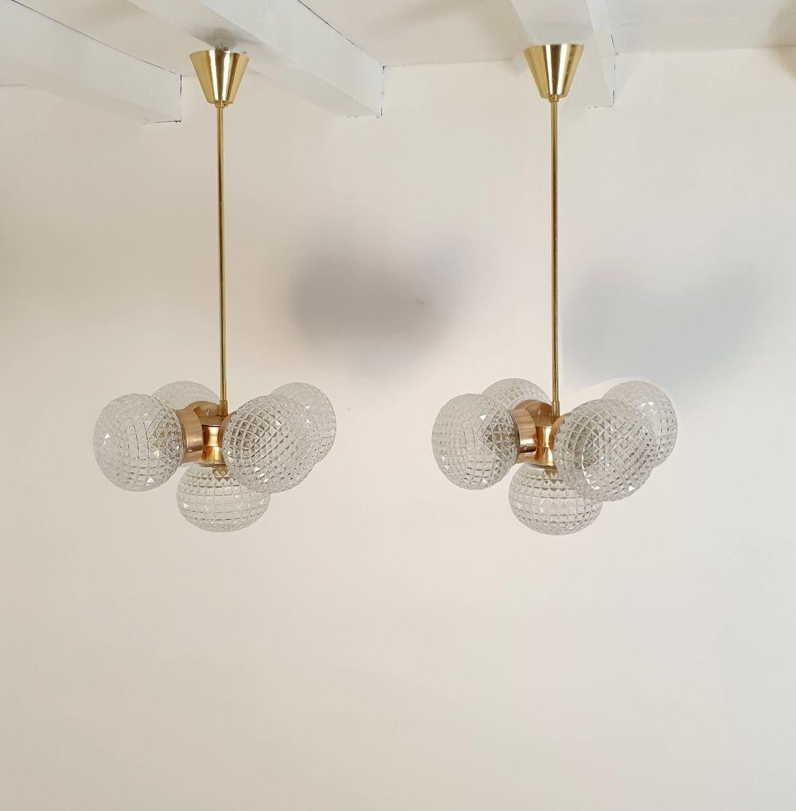 Coppia di lampadari in vetro di stile Mid-Century Modern provenienti dall'Italia, anni '80 circa.
Venduto e prezzato in coppia.
I lampadari a sospensione sono composti da 5 sfere di vetro e supporti in ottone.
I bicchieri hanno un disegno regolare