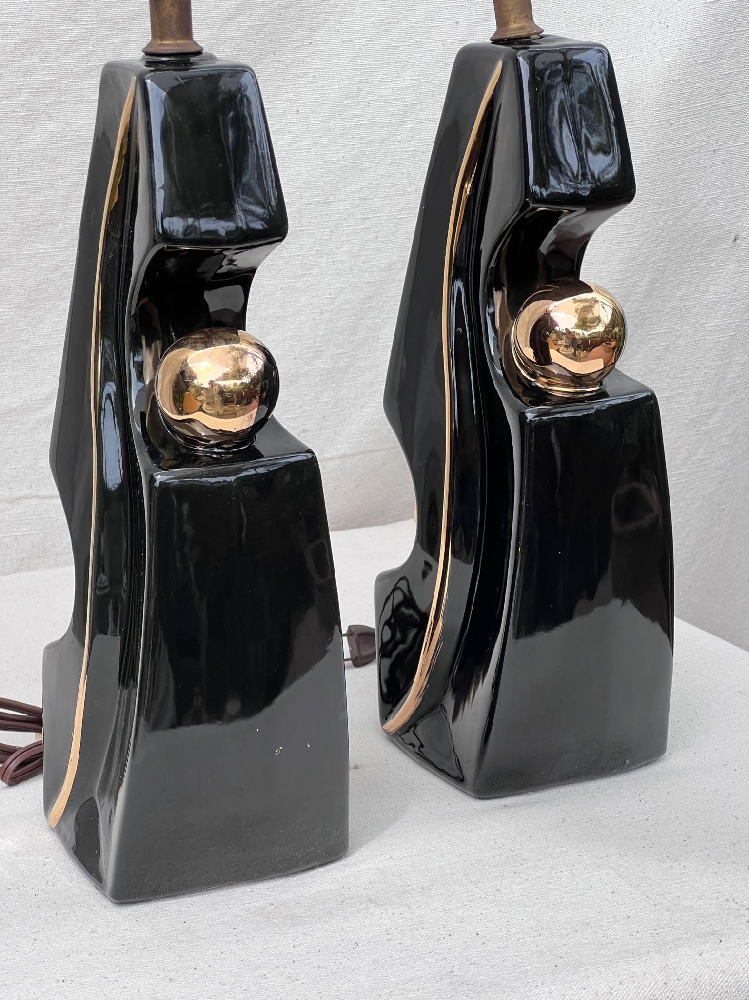 Our pair of mid-century modern glazed pottery table lamps takes inspiration from Picasso's distinctive style. These lamps showcase a harmonious blend of black and gold, adding a touch of opulence.