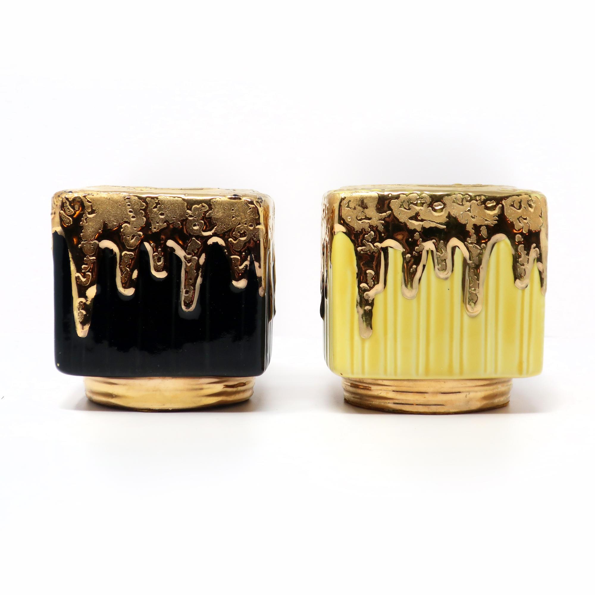 A fantastic pair of Mid-Century Modern ceramic planters with a gold metallic glazed foot and dripped top. One planter's under glaze is yellow and the other is black while the gold glaze has a lava quality to it.

In good vintage condition with