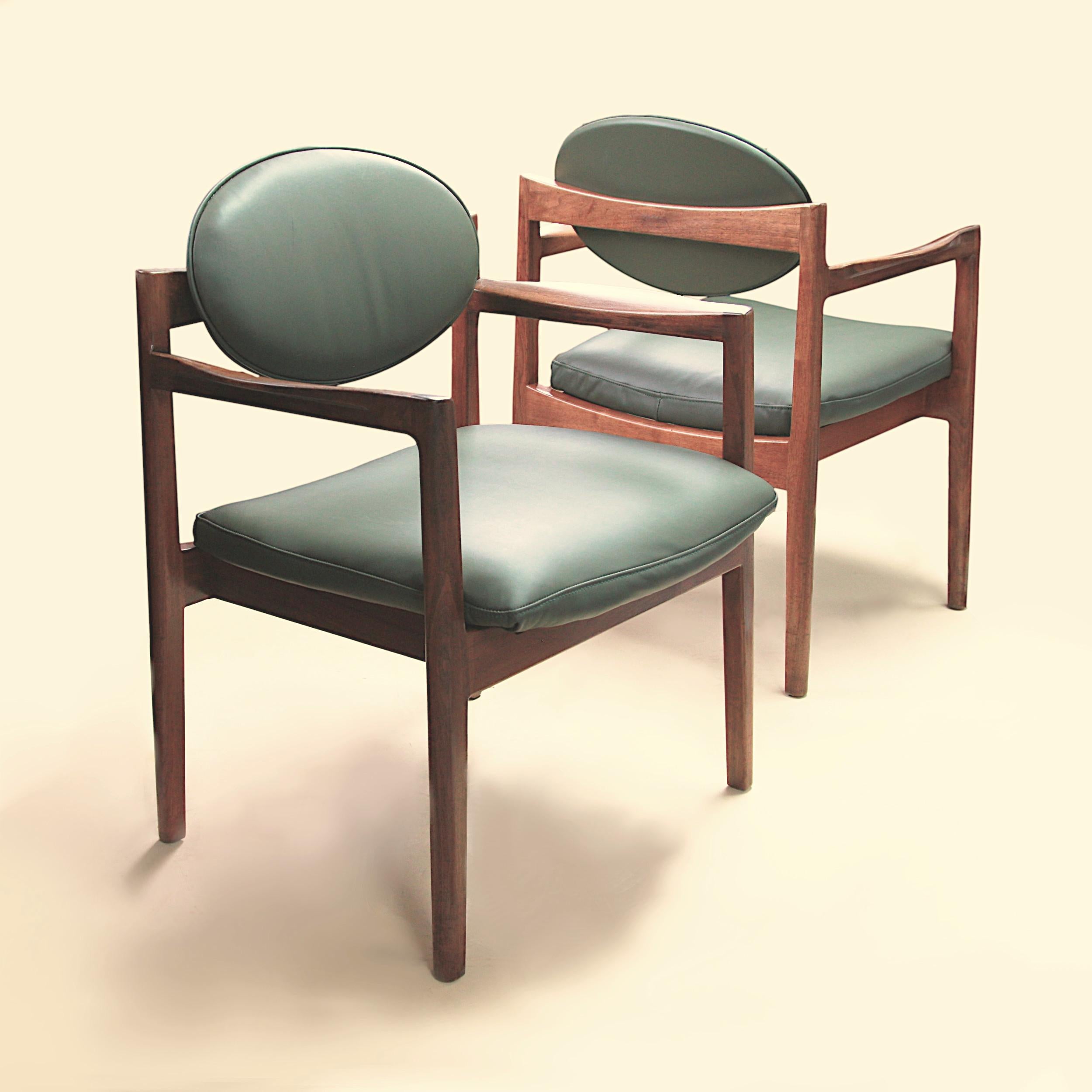 A fantastic pair of Mid-Century Modern green leather and walnut club chairs by Danish American designer Jens Risom. From the 1960s, these chairs are in very nice vintage condition. Chairs feature a gorgeous, sculptural design, beautifully