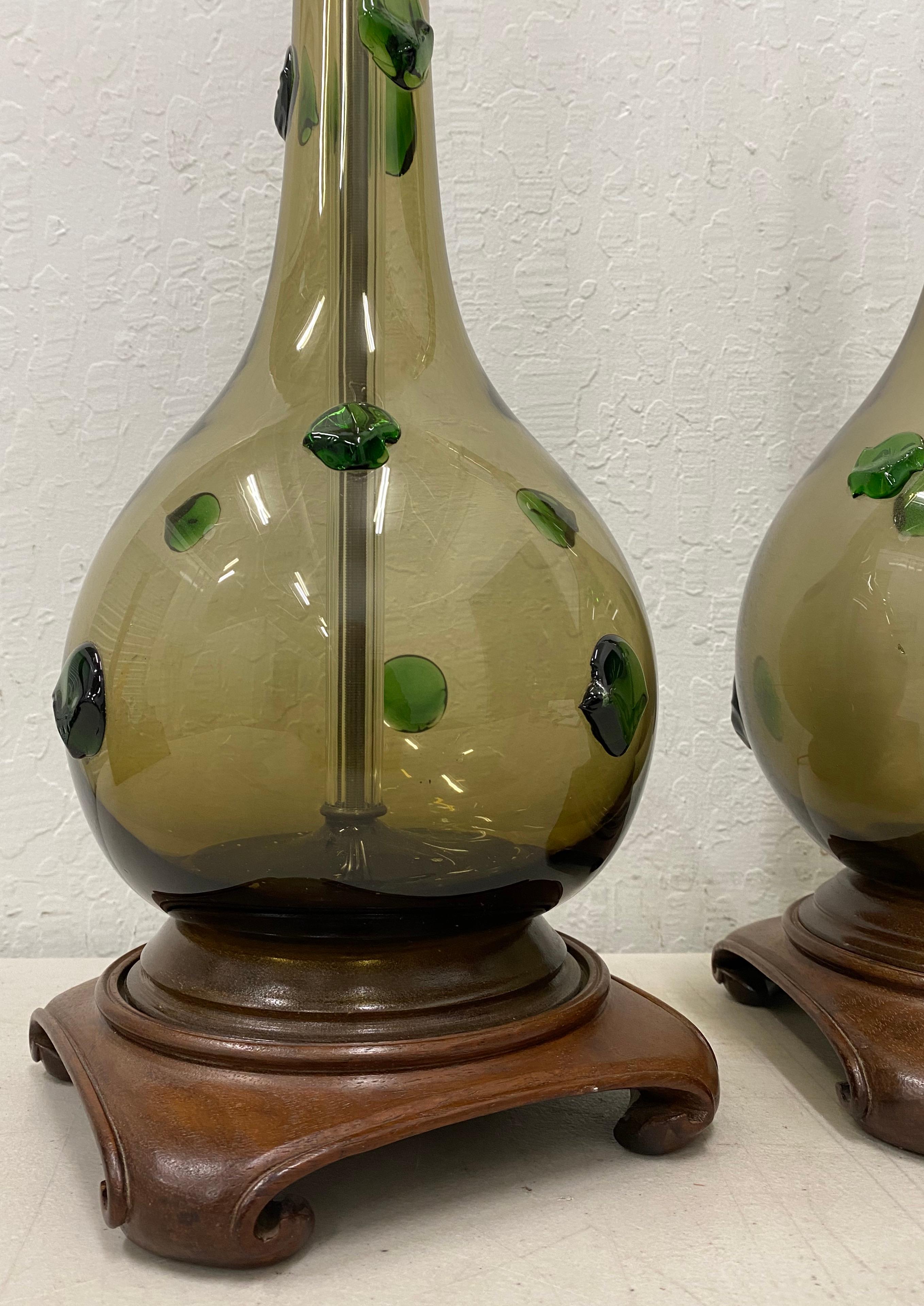 Pair of Mid-Century Modern hand blown glass lamps with green prunt drops

Gorgeous midcentury table lamps.

Each lamp is hand blown and has green candy-like prunt drops

The lamps sit atop hand carved walnut bases

Dimensions 8