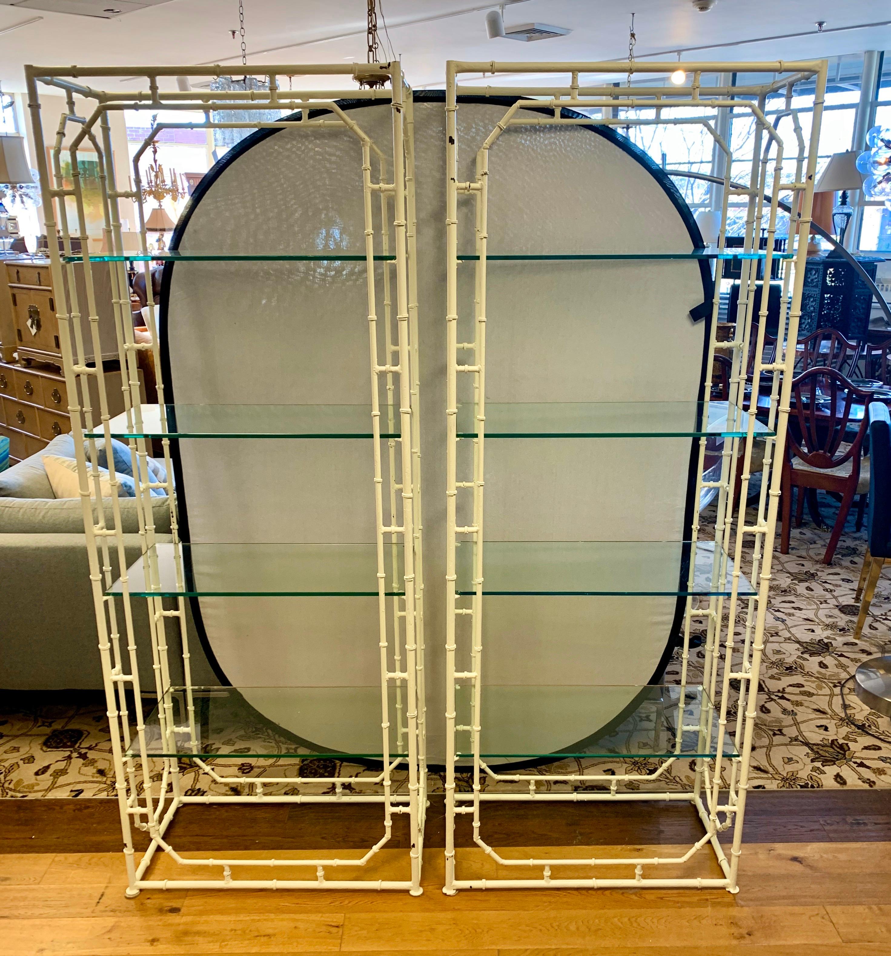 Pair of matching white hand painted étagères, circa 1970s with original, thick glass shelves. These metal
étagères have been hand painted white in the last ten years. The glass shelves are thick and most do have minor chips, although they are hard