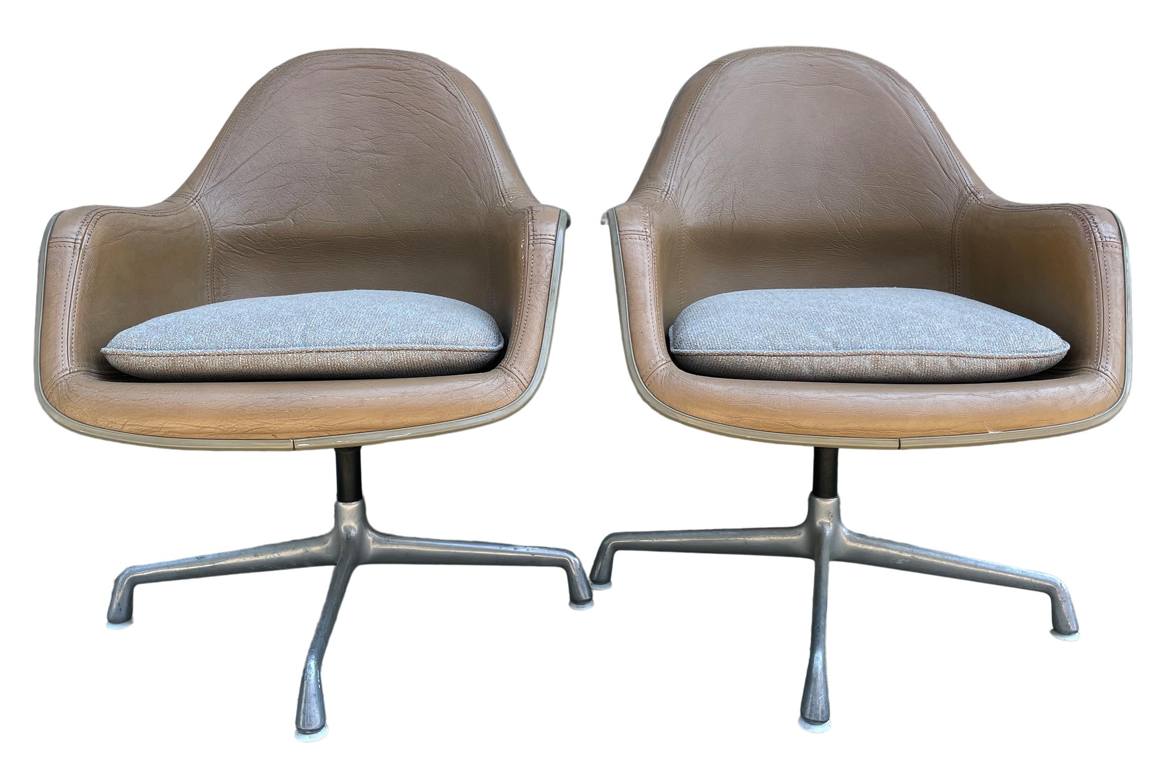 Mid-Century Modern Herman Miller leather lounge shell chairs. Tan/brown leather upholstered fiberglass shell chairs with woven fabric upholstered seat cushion. The chairs swivel on an aluminum base on plastic glides. Labeled and documented. Good