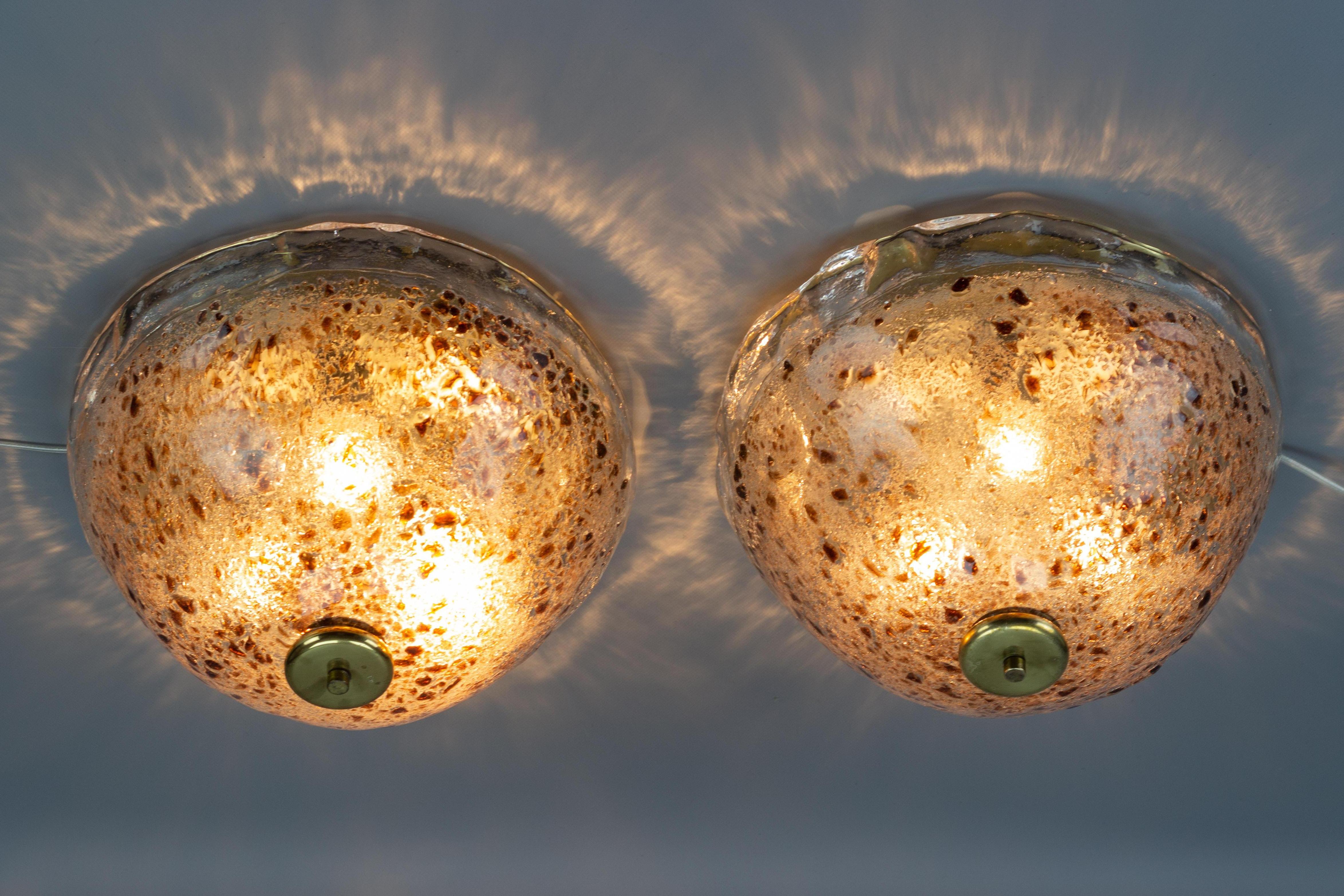 An impressive pair of round flush mounts, made of thick ice glass with red-brown accent inclusion. 
The beautiful and massive glass lamp shades are hand-blown, therefore - slightly different.
Brass fixture with three sockets for E27 (E26) size light