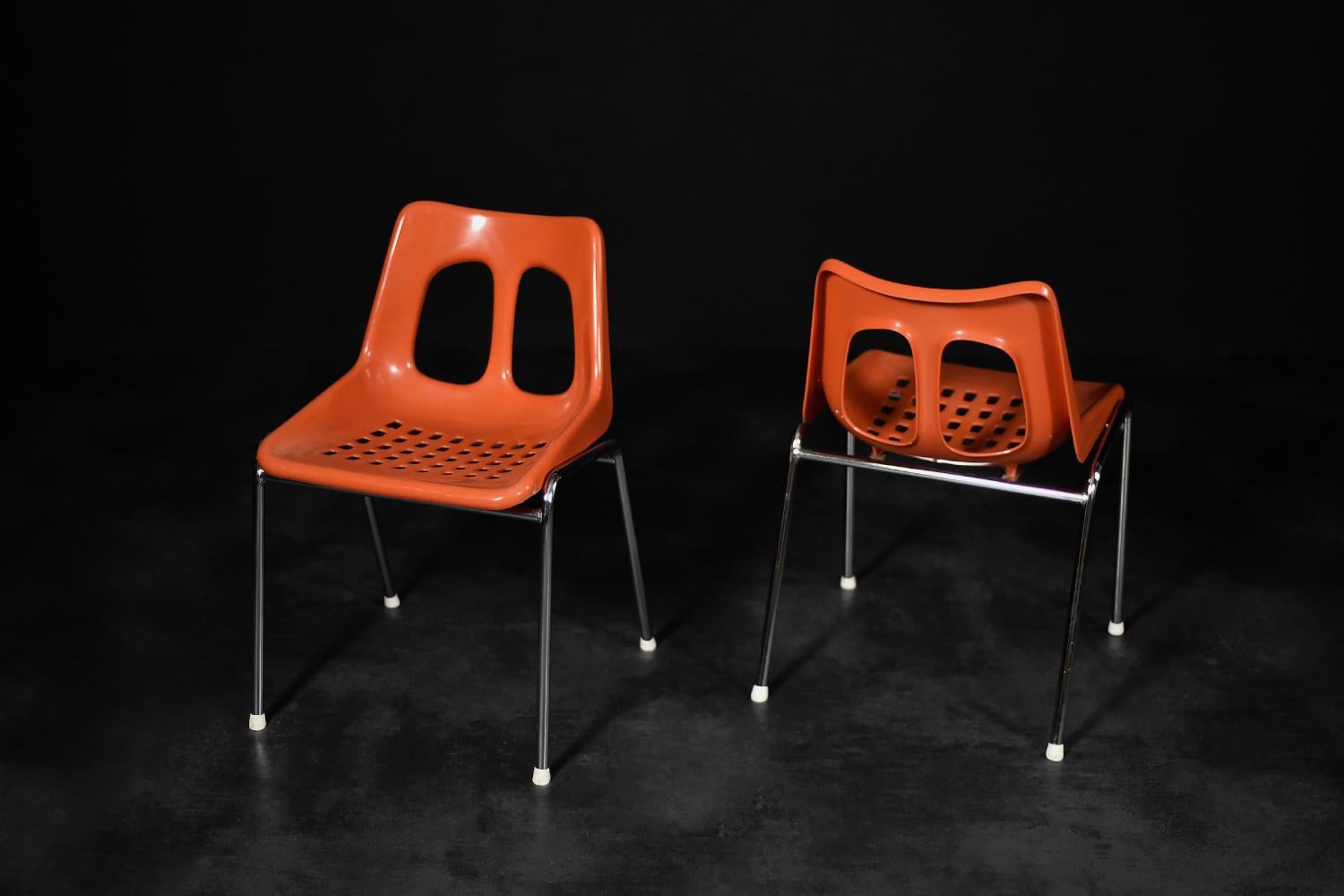 Dieses Paar modernistischer Stühle wurde in den 1960er Jahren von der israelischen Fabrik Plasson hergestellt. Der Sitz und die Rückenlehne sind aus orange-rotem Kunststoff geformt. Die schlanken Beine sind aus verchromtem Metall gefertigt. Die