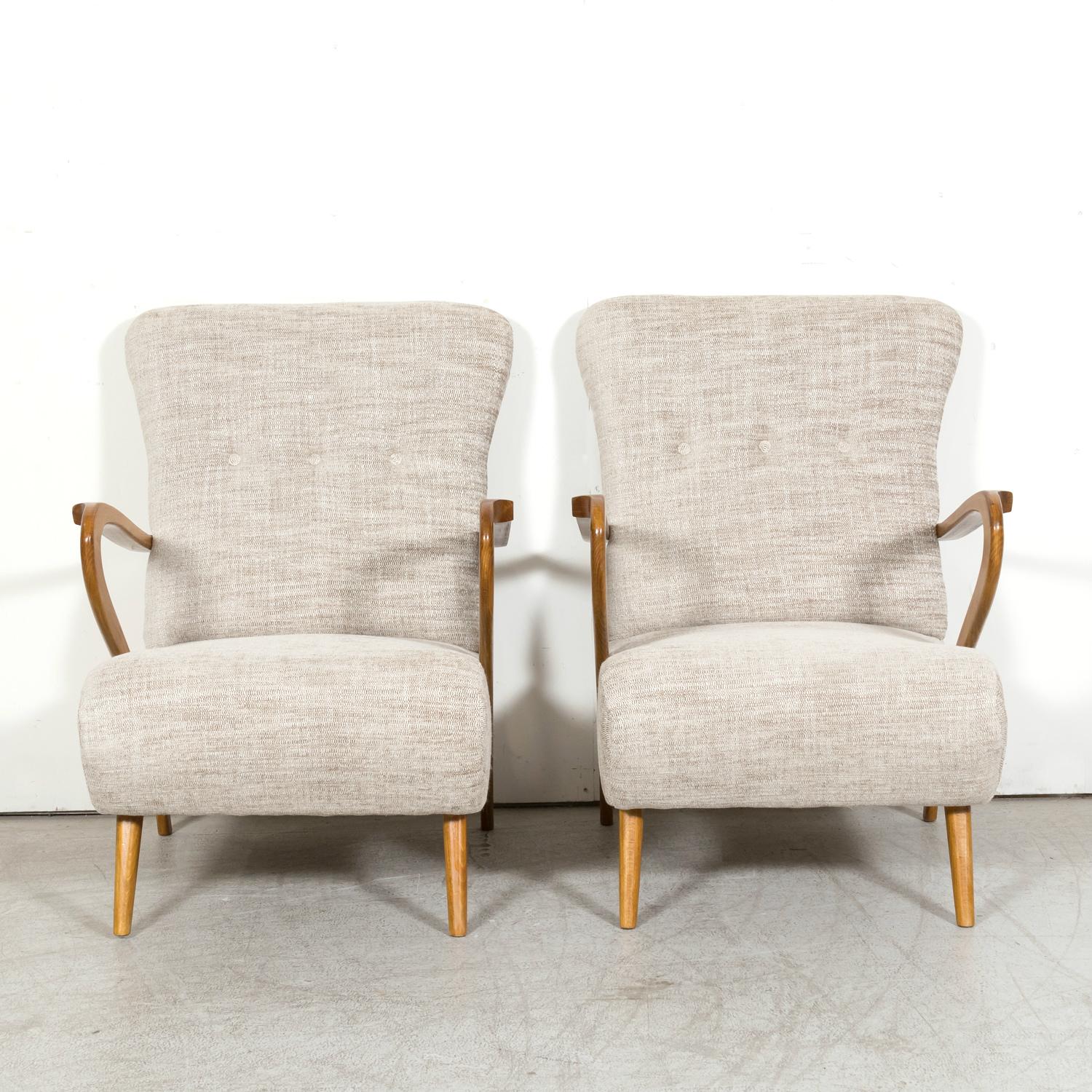 A distinctive pair of mid-Century modern Italian armchairs in the style of Paolo Buffa, a fine Italian manufacturer, circa 1950s. Having high backrests with a gentle incline that offers comfort and support, sculpted sinuous hardwood arms, and short