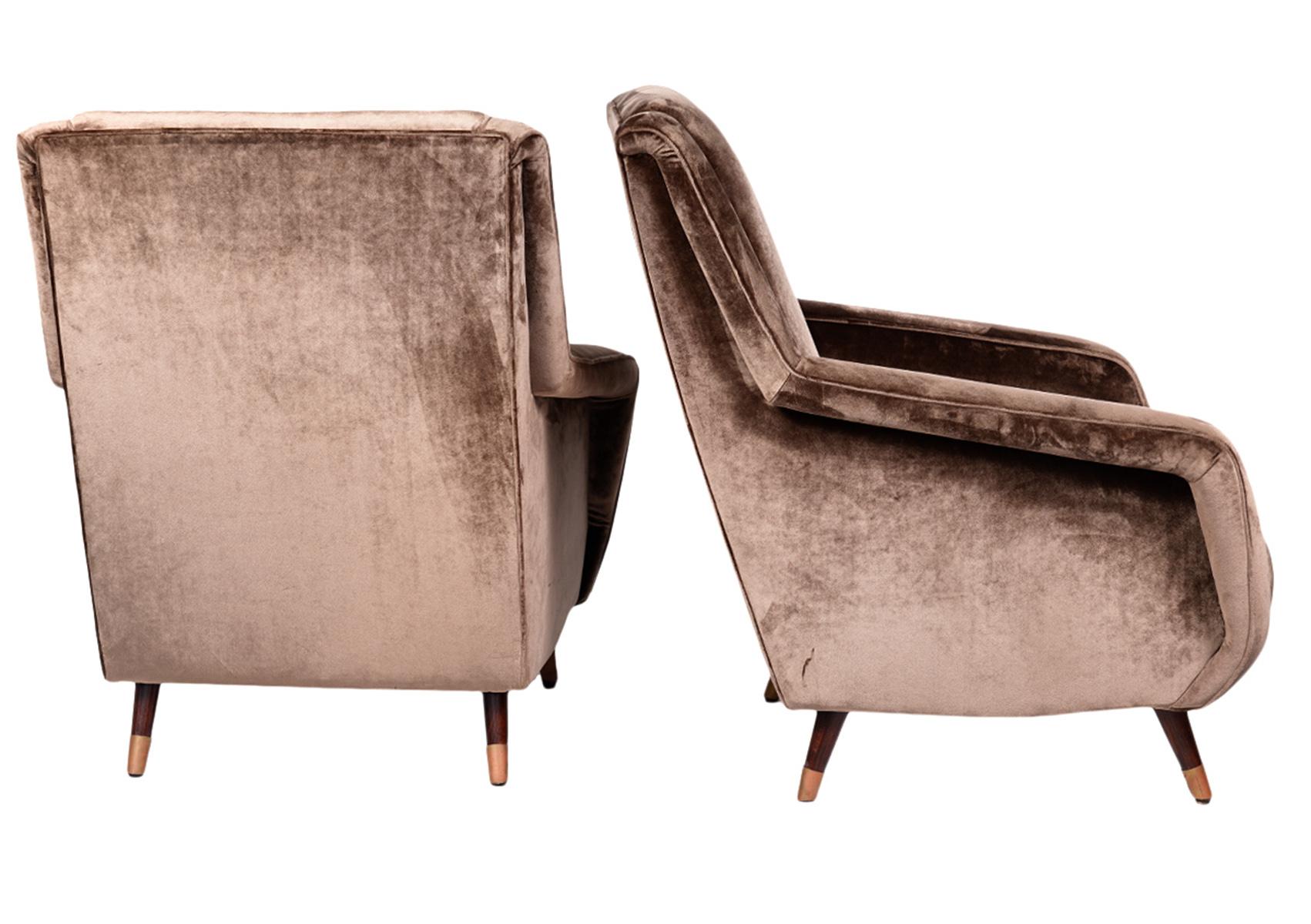 Resting on four round tapering wood legs with copper sleeves these easy chairs or lounge chairs display their sculptural form to the fullest. The slightly downwards slanted armrests is quite a unique design. The velvet cover is full of life changing