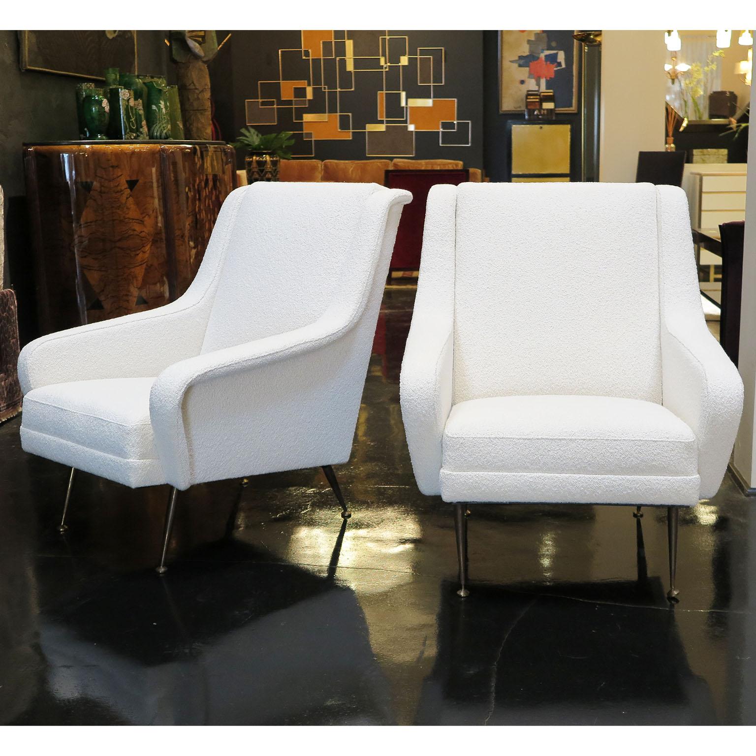 These sleek Mid-Century Modern lounge chairs from Italy by Carlo de Carli feature angled arms and distressed brass tapered legs. Upholstered in an ivory Boucle fabric allows these chairs to be timeless in any interior.