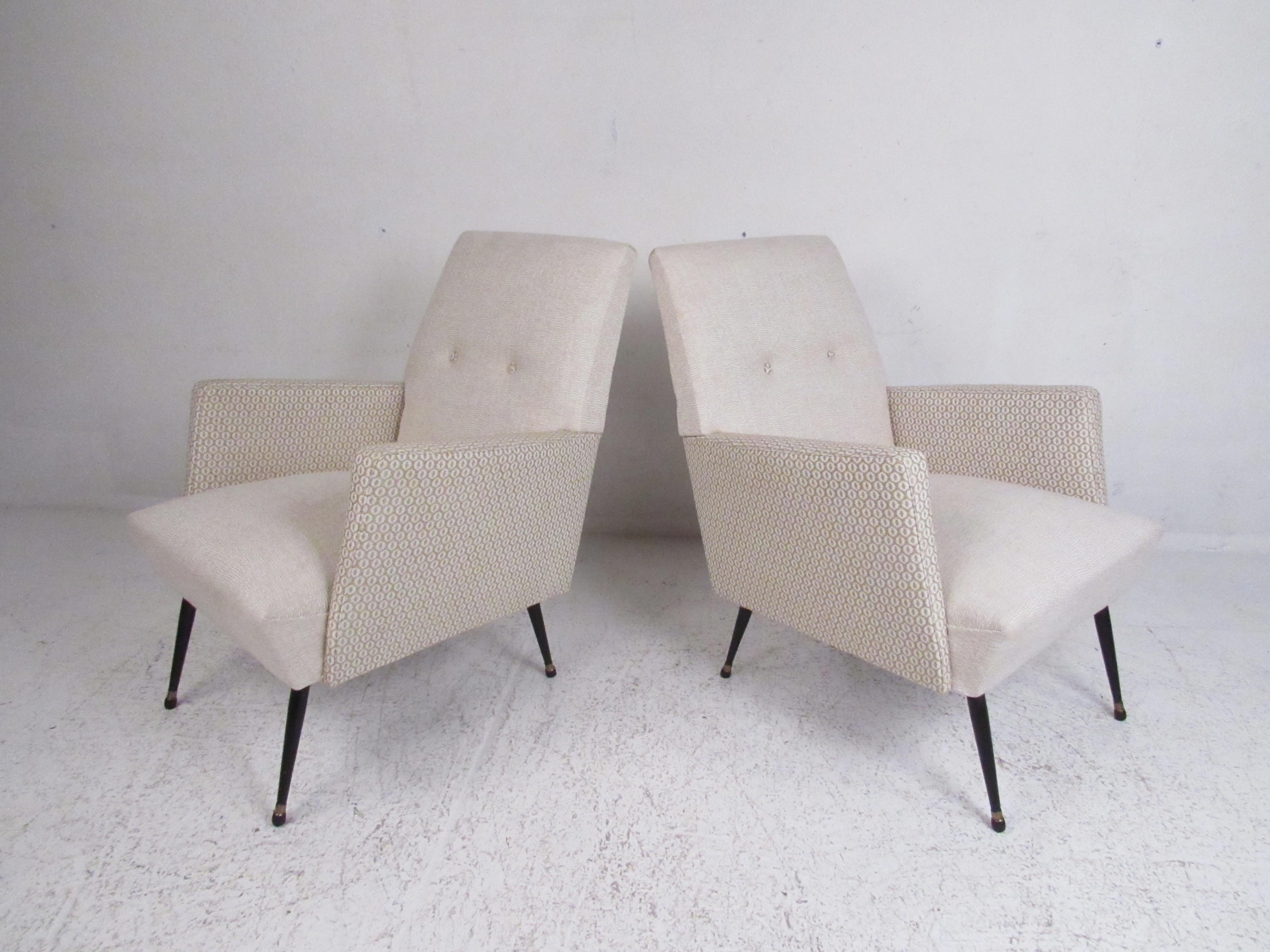 This beautiful pair of vintage modern armchairs feature cream-colored fabric with decorative armrests. The plush upholstery, tufted backrest, and splayed legs add to the midcentury appeal. This stylish pair of chairs make the perfect addition to any