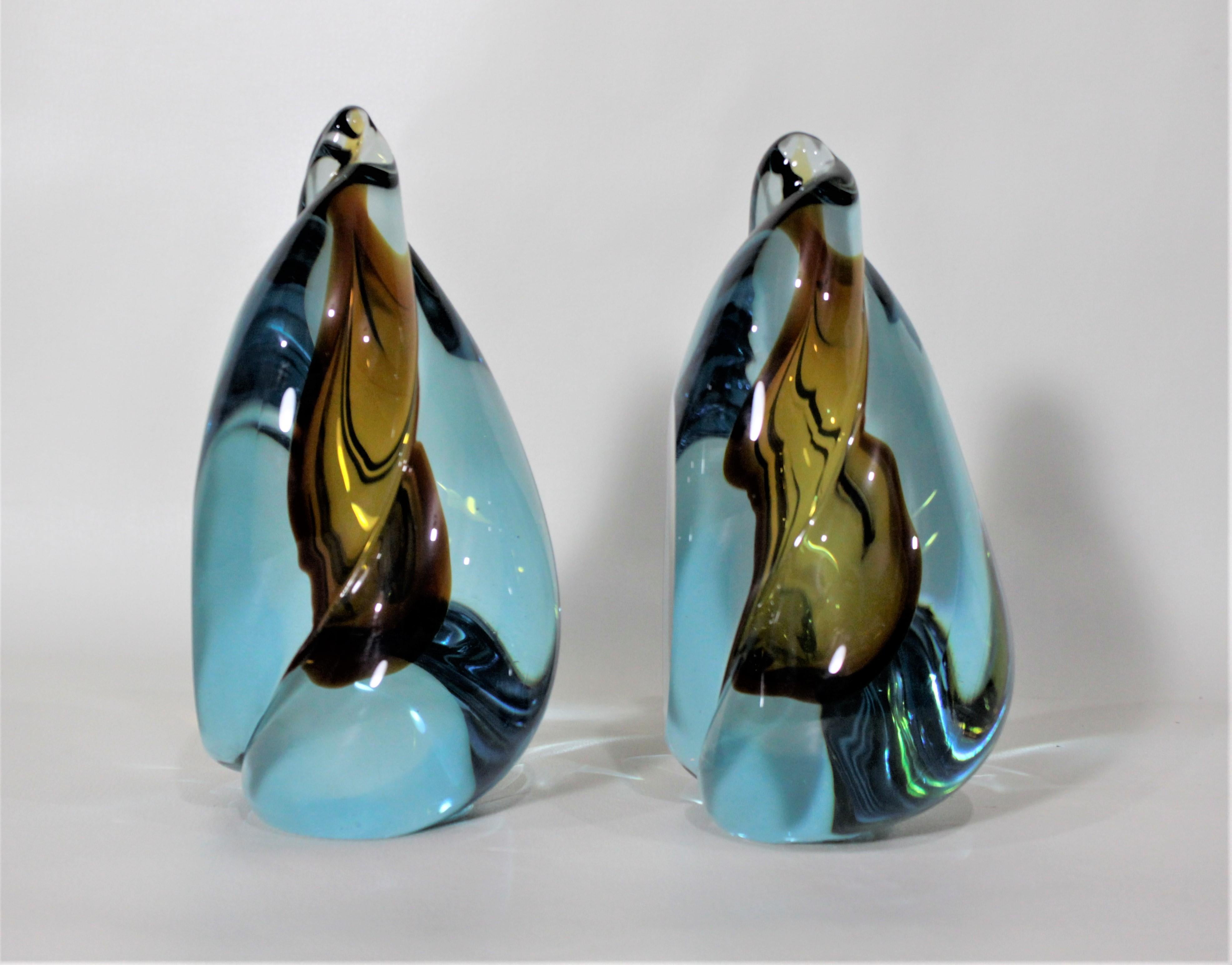 This pair of Mid-Century Modern art glass bookends were made in Italy during the 1960s and can be attributed to the works of the art glass designer, Alfredo Barbini. Each bookend is done with a swirled blend of three pieces using blue and amber