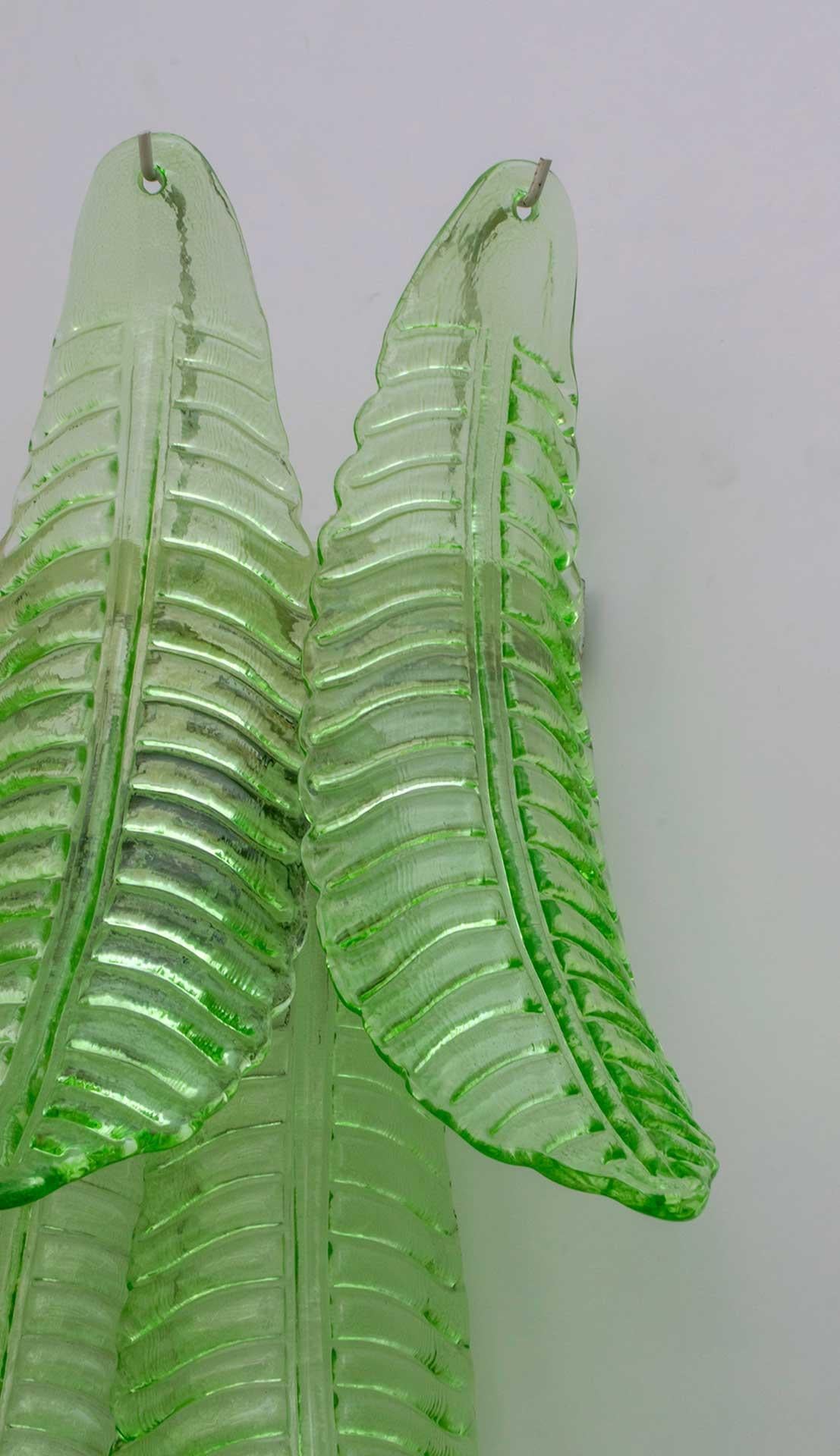 Paire d'appliques en verre soufflé vert de Murano, support en métal, deux ampoules.
Ces appliques sont également des sculptures qui reproduisent les feuilles d'un palmier.