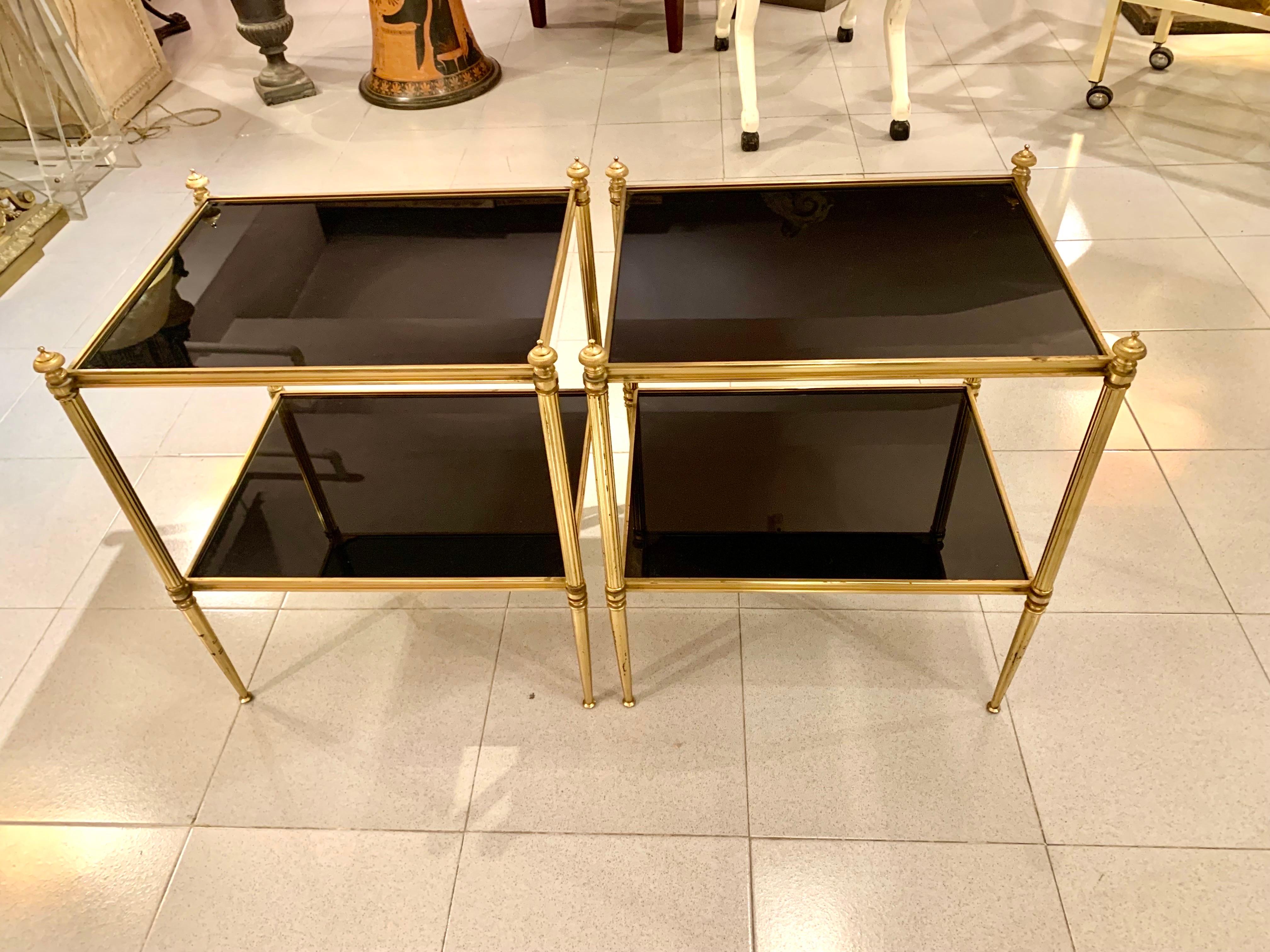 A pair of French Maison Jansen-style tables based on the Louis Xvi model, in gilded brass and two trays with black glass tops are very decorative tables with various uses, in Good condition.