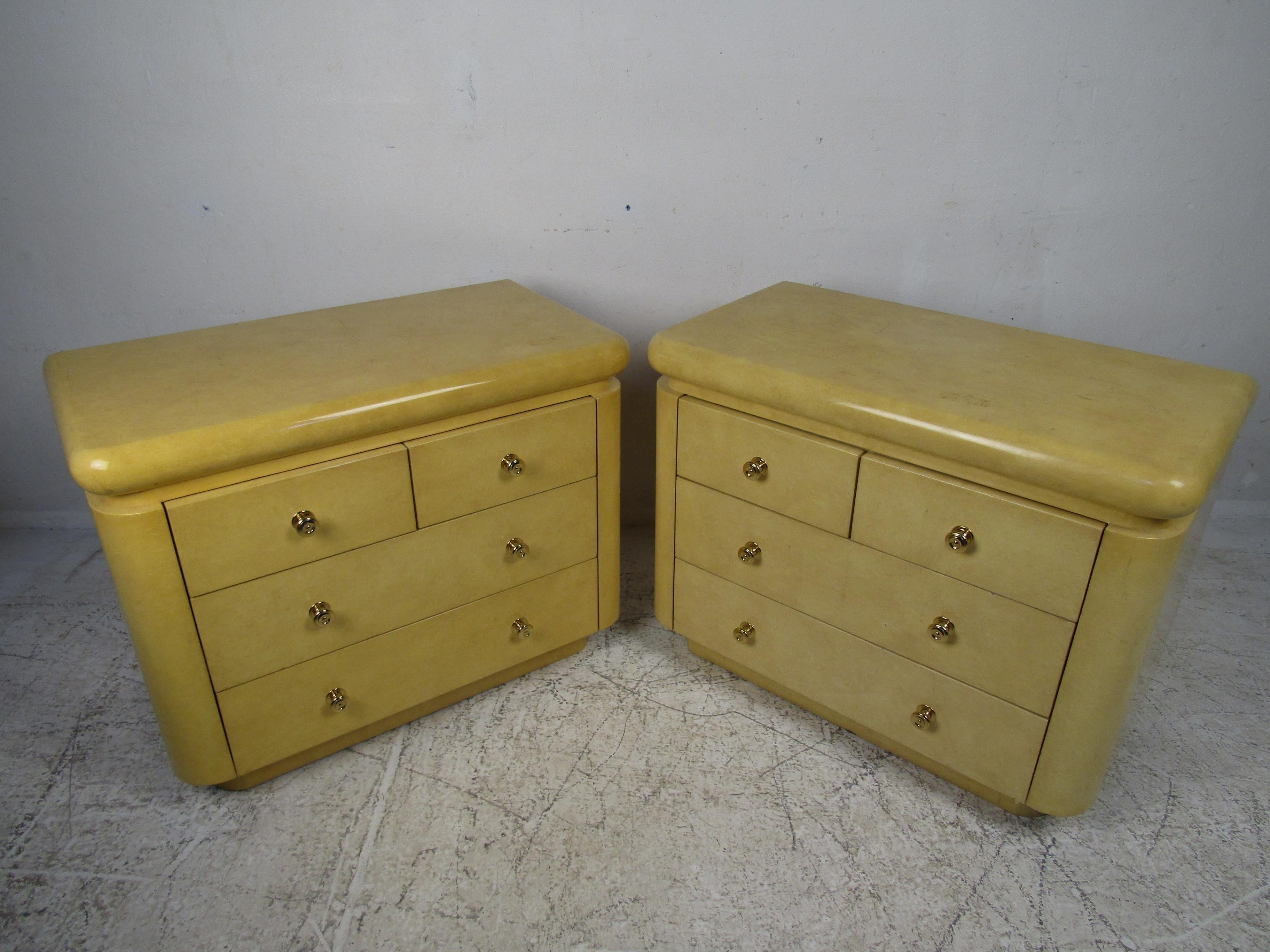 This elegant pair of vintage modern nightstands feature plenty of room for storage within its many drawers. A wonderful design covered in lacquered goatskin with unusual brass handles. A uniquely shaped pair that is sure to add style and grace to