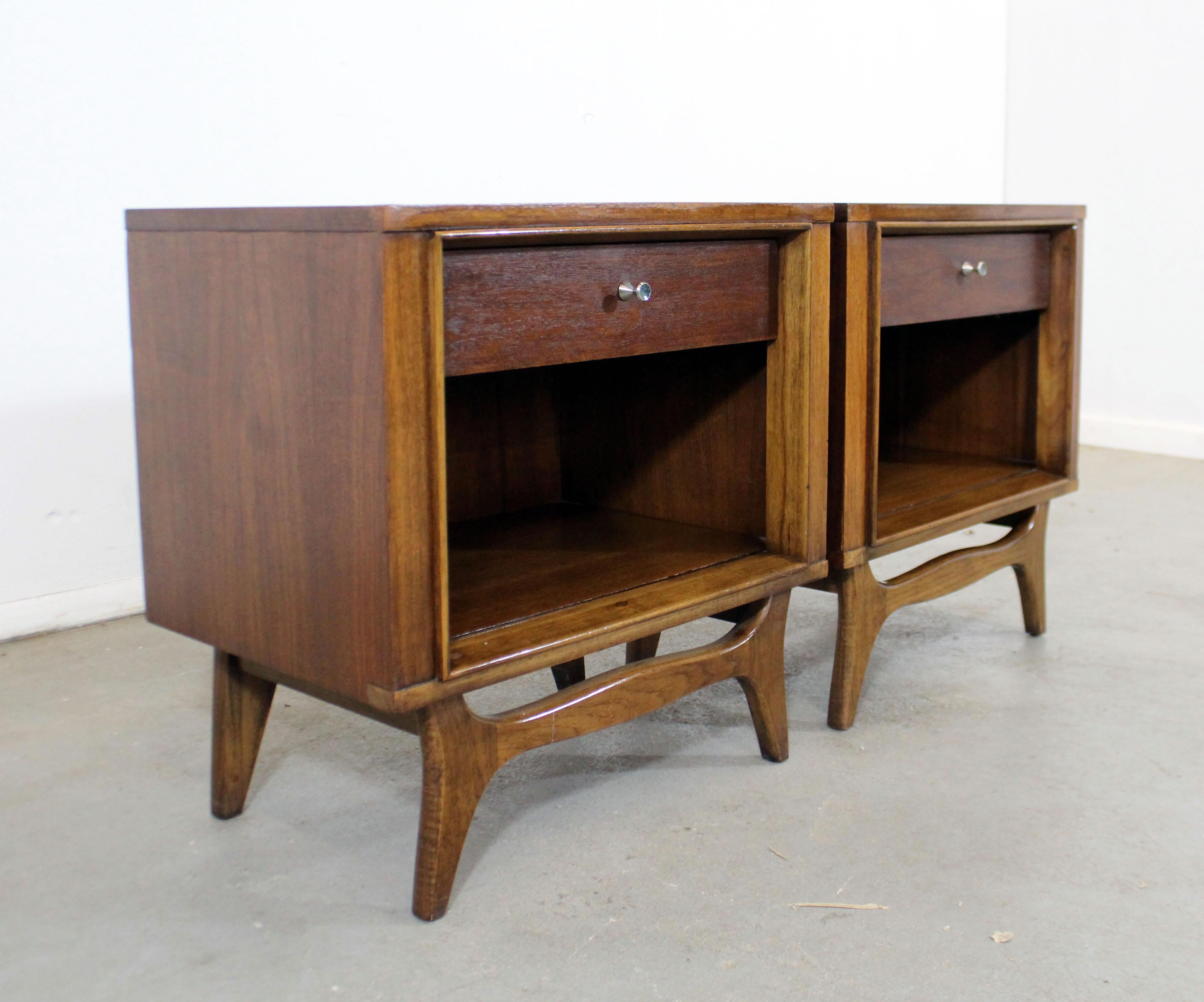 Offered is a pair of Mid-Century Modern nightstands by Kent Coffey's 'Insignia' line. This set is made of walnut, with each featuring one dove-tailed drawer and open storage cabinet. They are in good condition, showing minor age wear (previous
